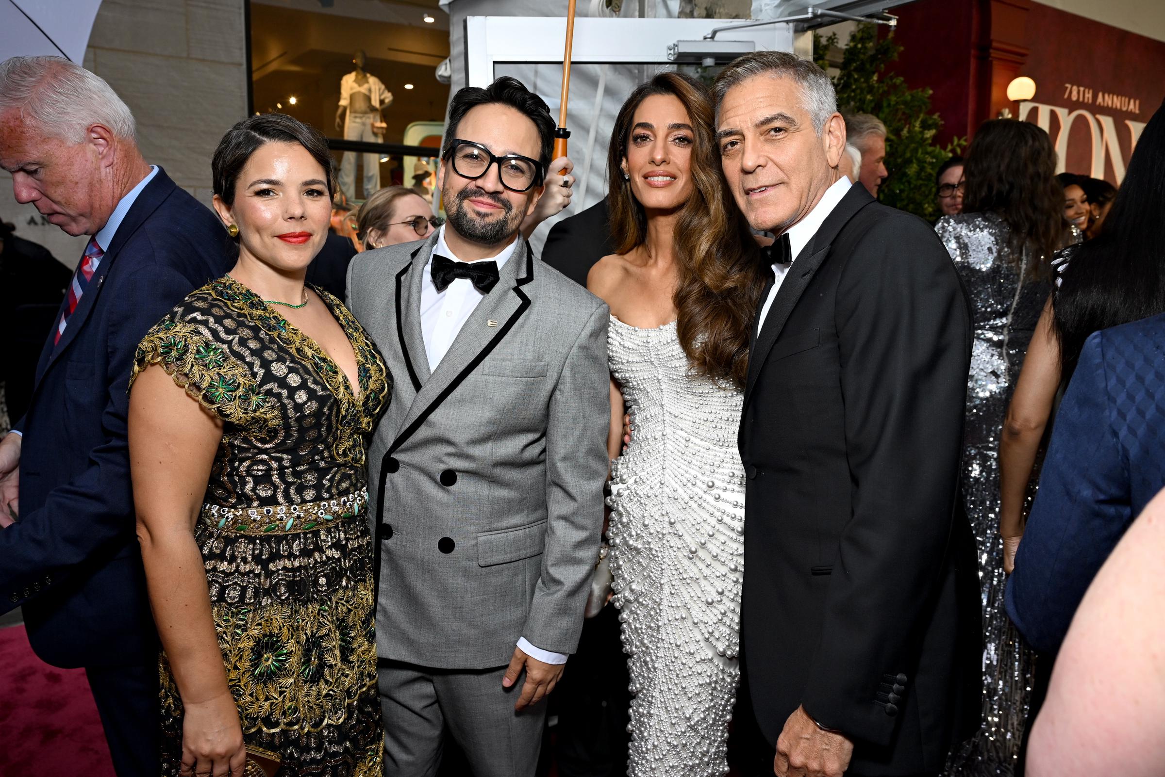 George et Amal Clooney se joignent à Lin-Manuel Miranda et Vanessa Nadal pour une photo de groupe lors de la cérémonie des Tony Awards. La robe couverte de perles d'Amal ajoute un éclat à ce moment amical, tandis que George se penche avec un demi-sourire.
