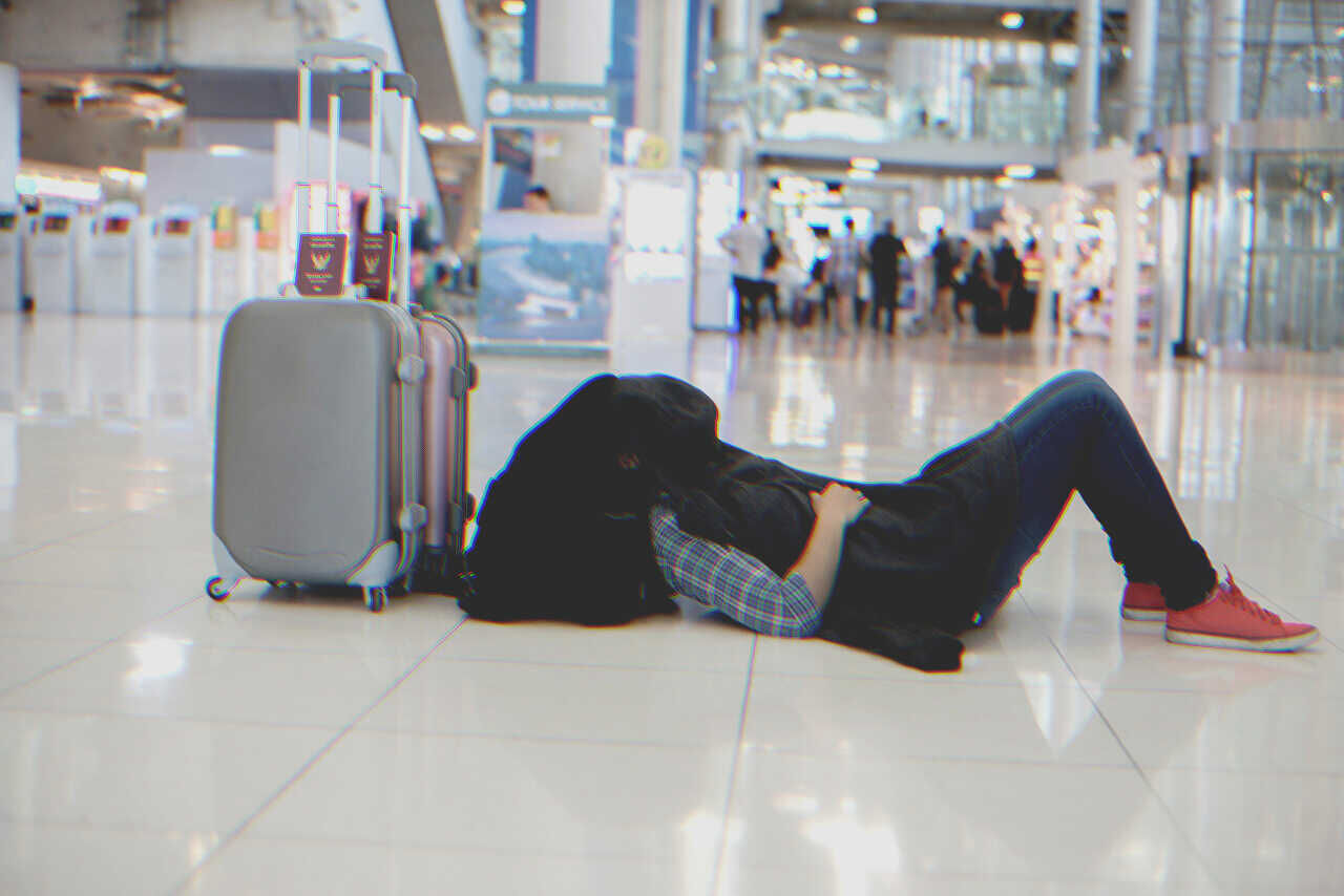 Homme allongé sur le sol de l'aéroport | Source : Shutterstock