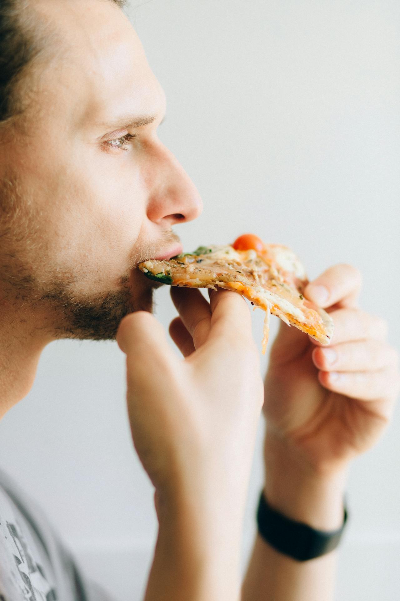 Un homme mangeant une pizza | Source : Pexels