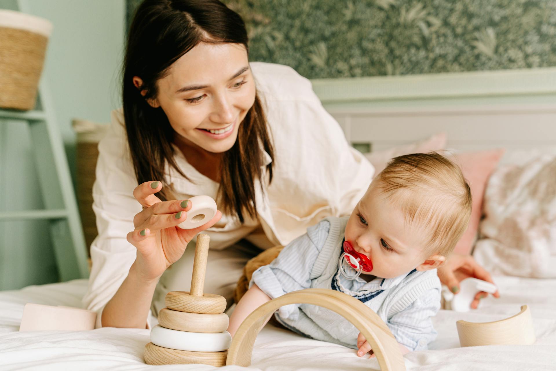 Une femme jouant avec son bébé sur un lit | Source : Pexels