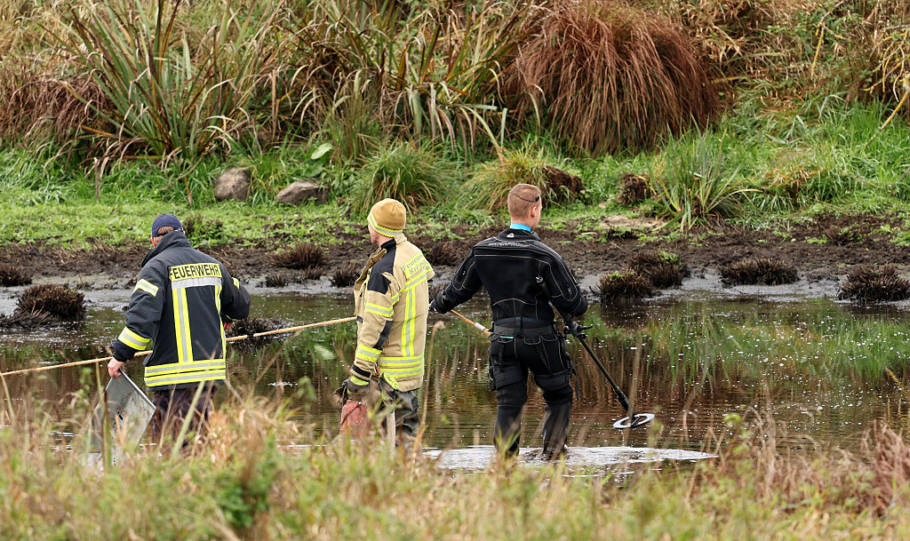 À l'endroit où Fabian, huit ans, de Güstrow, a été retrouvé mort dans un petit étang près de Klein Upahl, les pompiers pompent l'eau pendant qu'un policier se déplace avec un détecteur. | Source : Getty Images