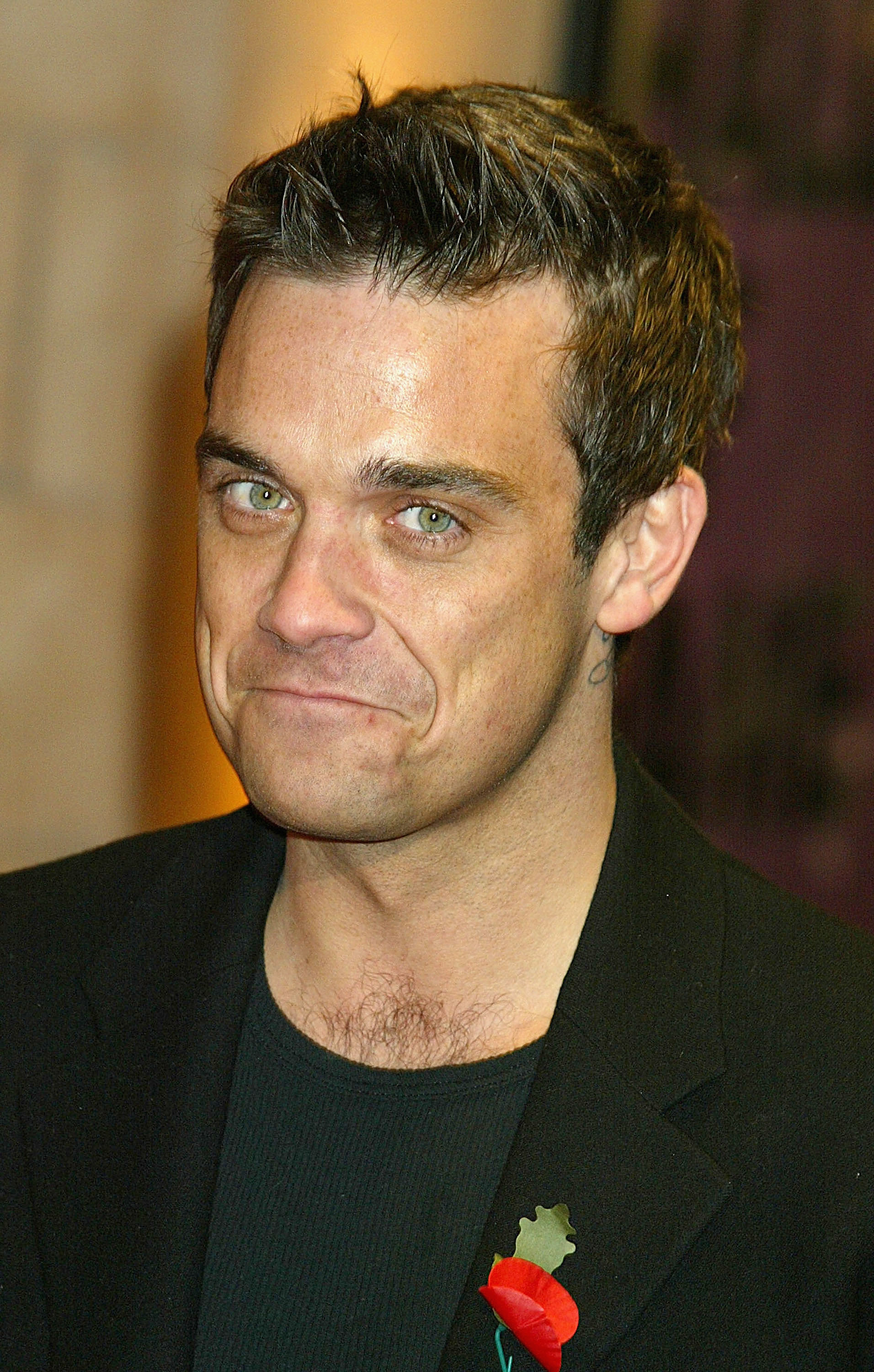 Robbie Williams à la finale du « UK Music Hall of Fame » le 11 novembre 2004 à Londres. Vêtu d'un blazer noir et arborant un pin's en forme de coquelicot, il a affiché un sourire complice, clin d'œil à son charisme et à son statut d'icône pop britannique incontournable.