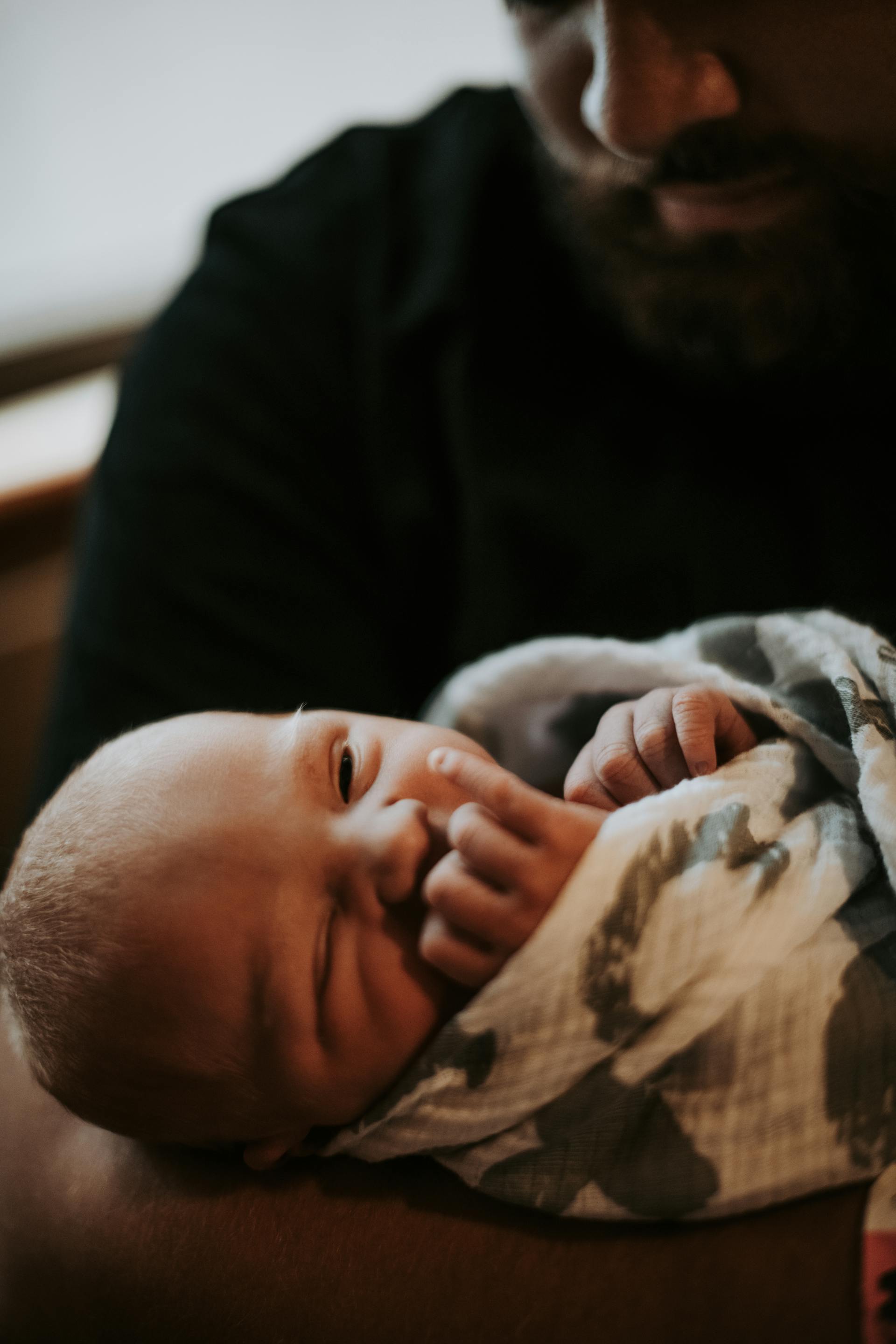 Un bébé emmailloté dans une couverture est tenu par un homme | Source : Pexels