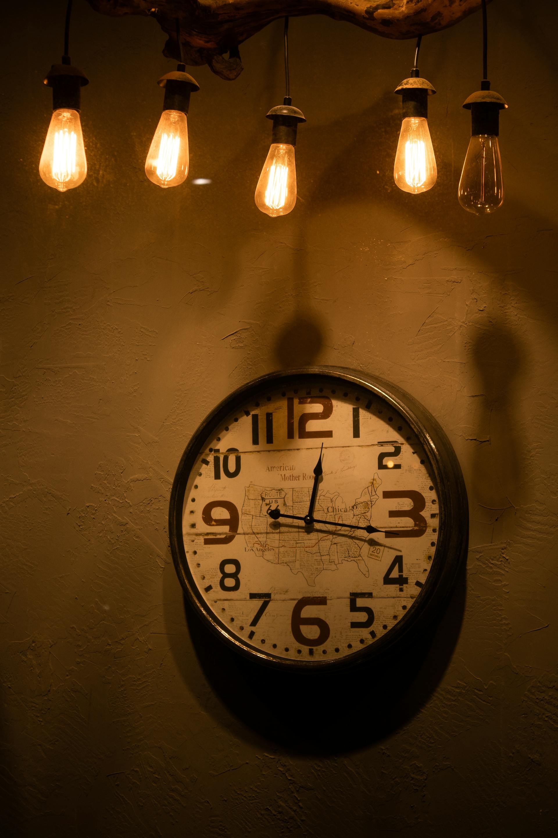 Des ampoules suspendues au-dessus d'une horloge analogique | Source : Pexels