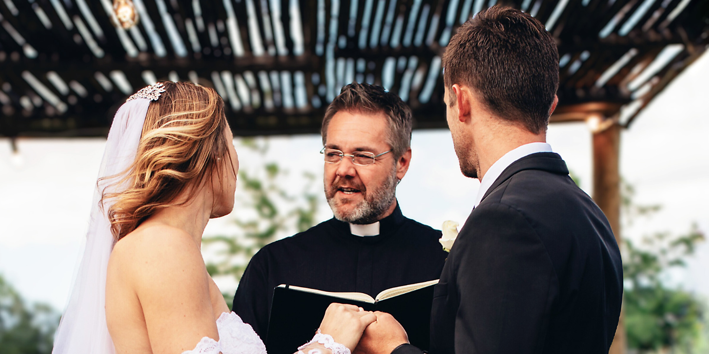 Une mariée et un marié face à un prêtre | Source : Shutterstock
