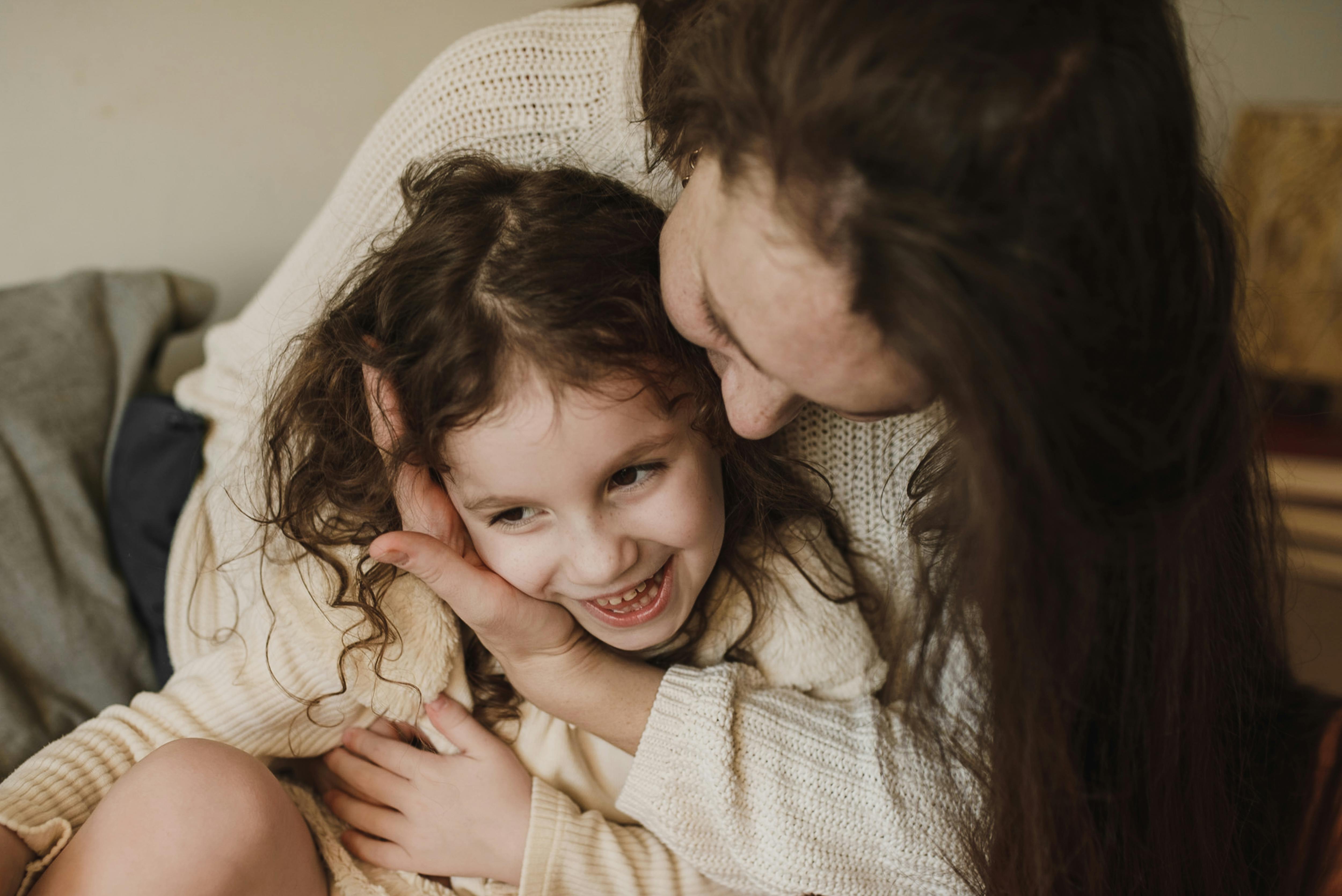 Une fillette heureuse assise sur les genoux de sa mère | Source : Pexels