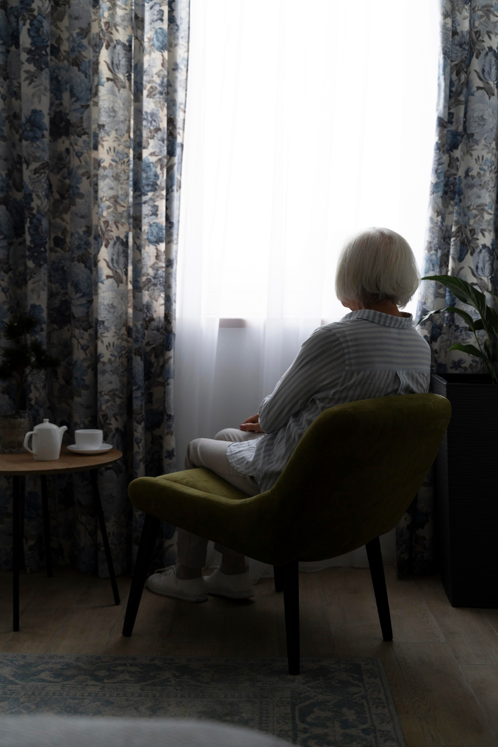 Une femme âgée solitaire assise dans une pièce | Source : Freepik