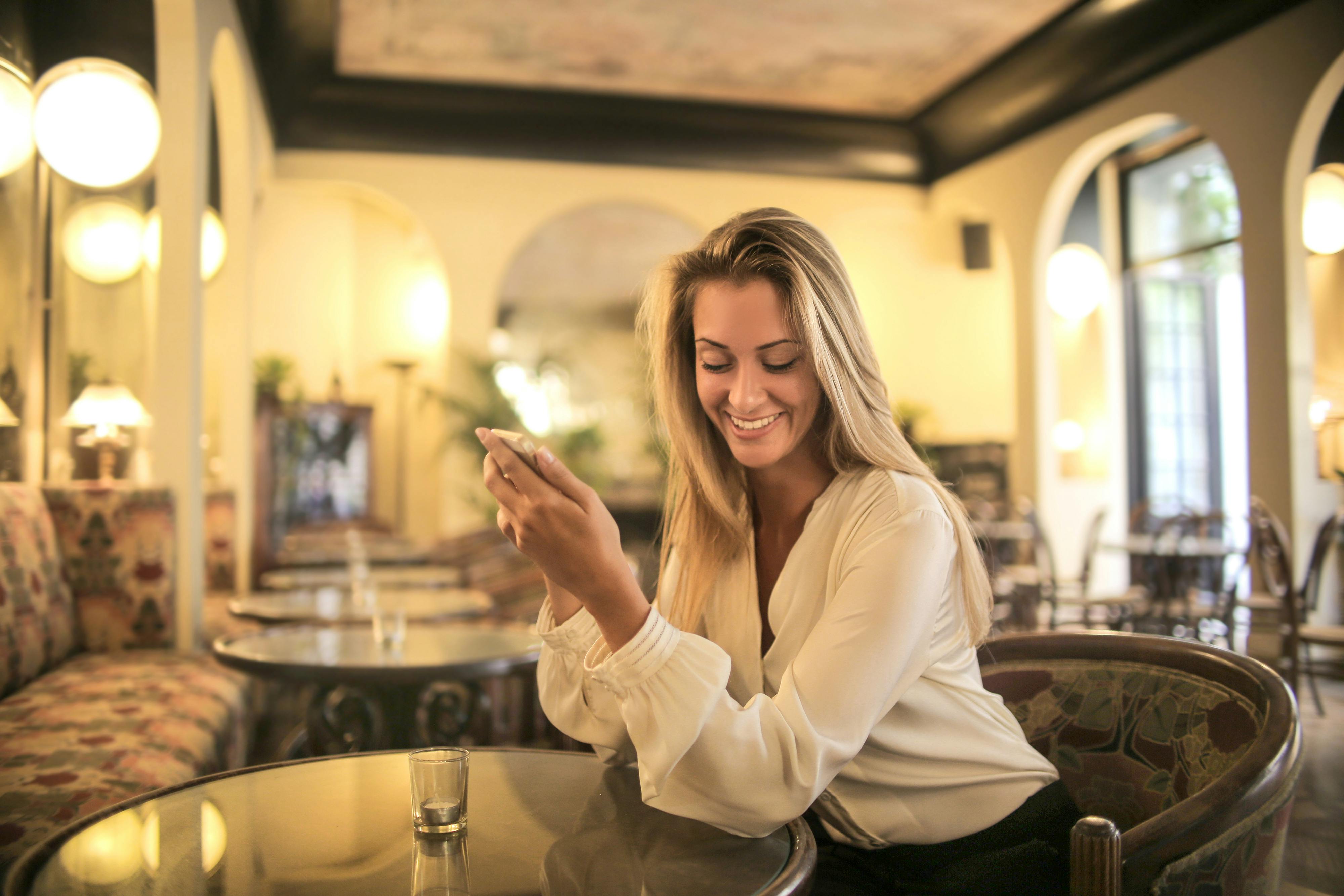 Une femme souriante assise dans un restaurant | Source : Pexels