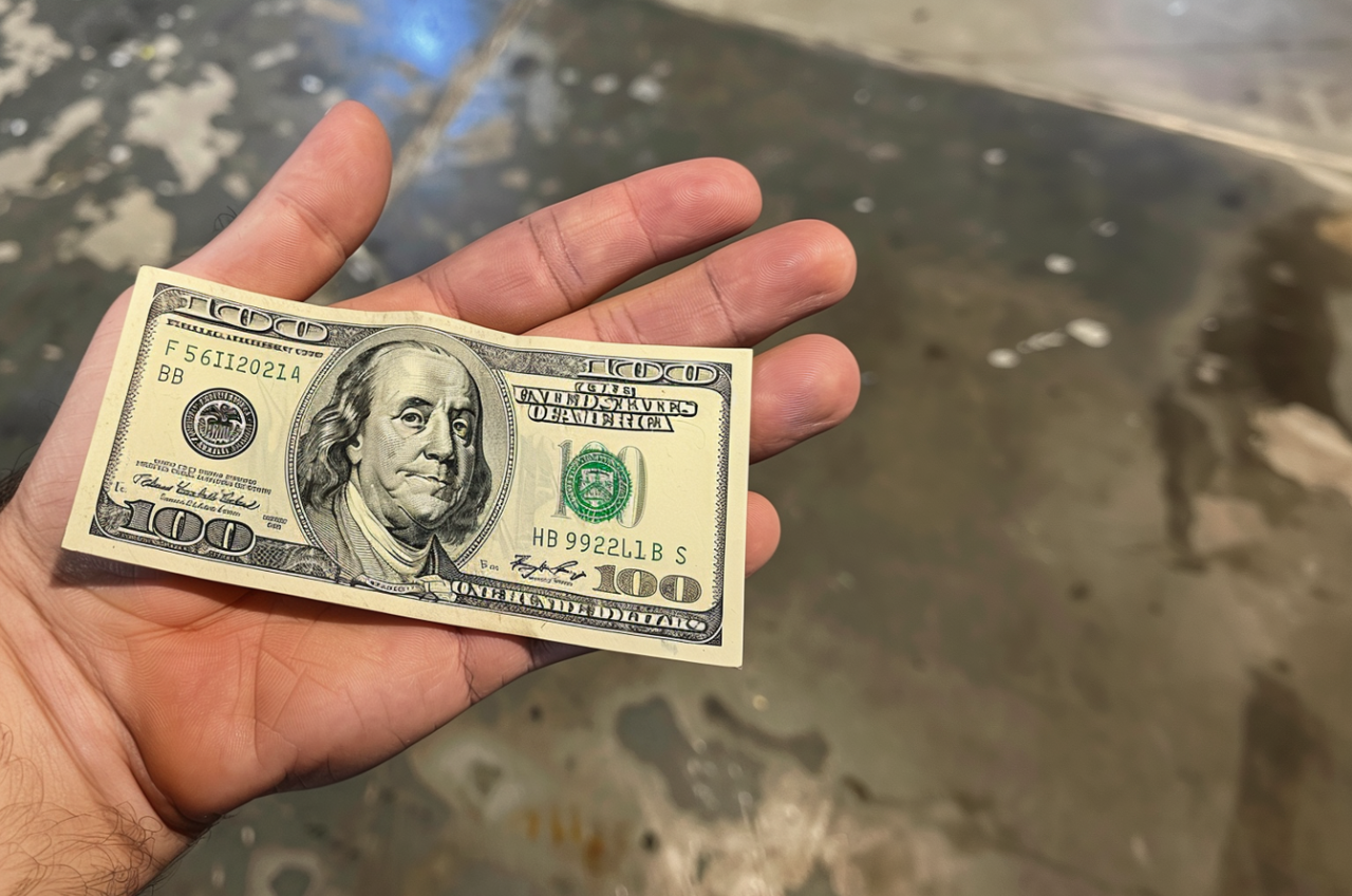 Un homme tenant un billet de cent dollars | Source : MidJourney