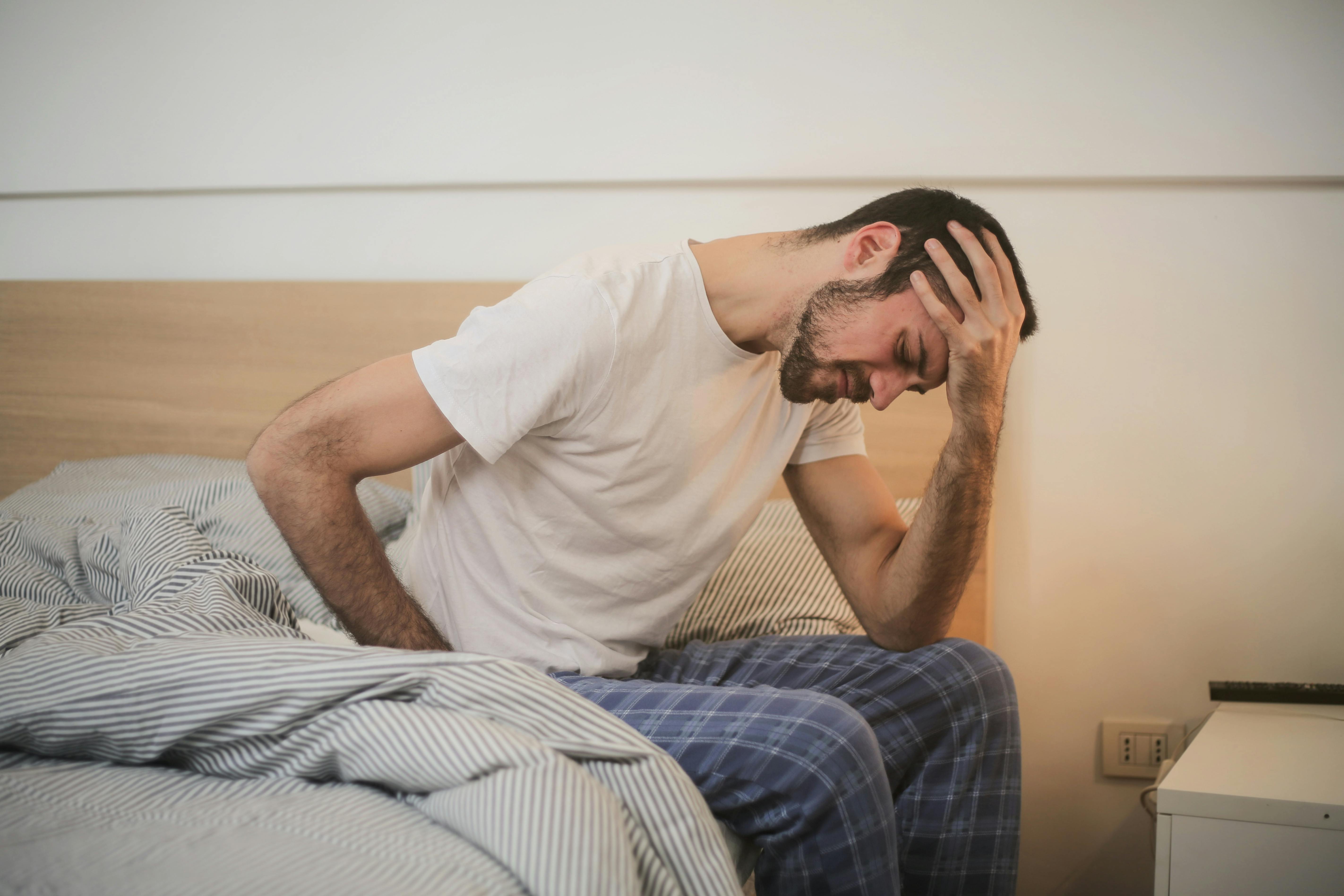 Un homme stressé assis sur un lit | Source : Pexels