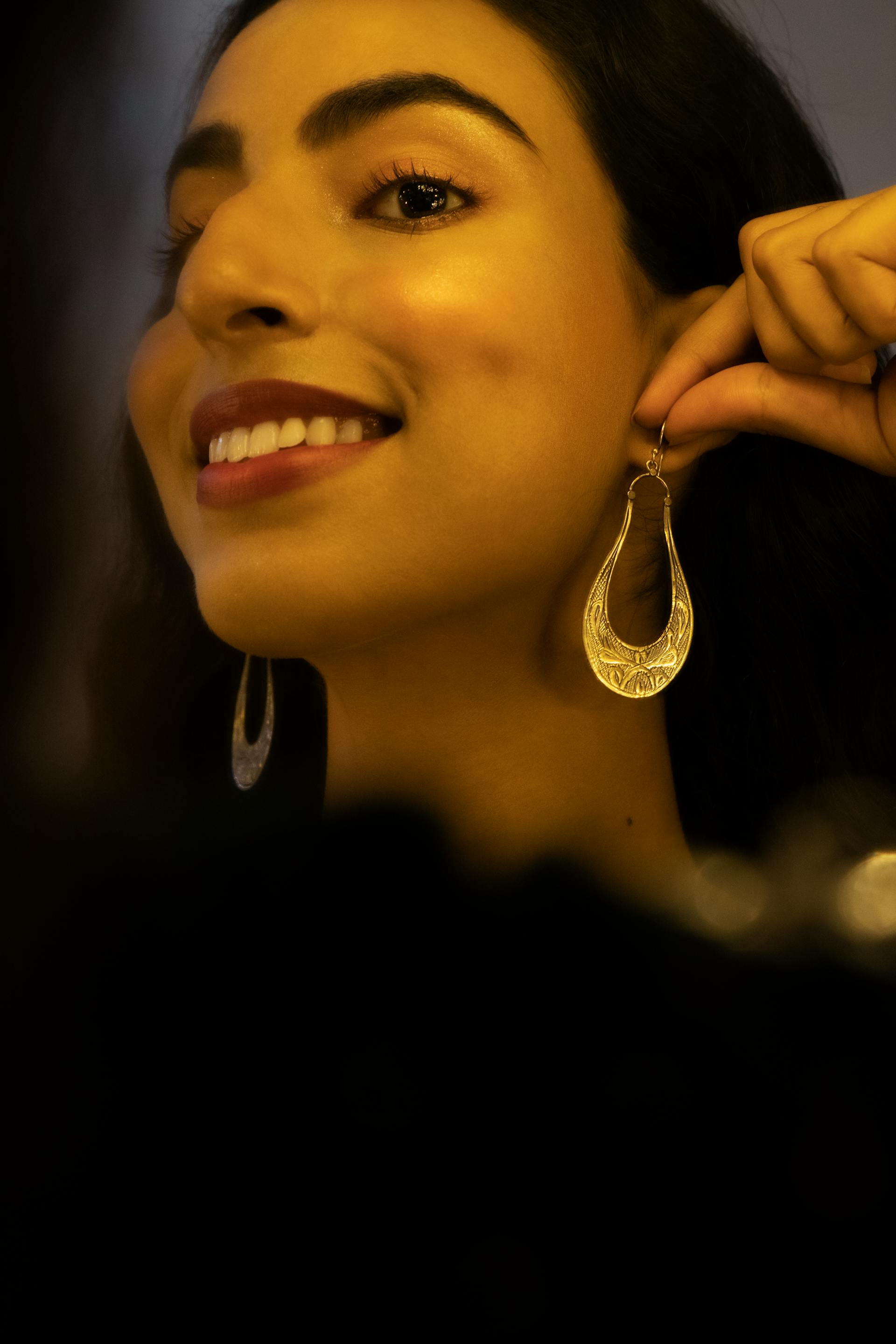 Une femme qui met des boucles d'oreilles | Source : Pexels