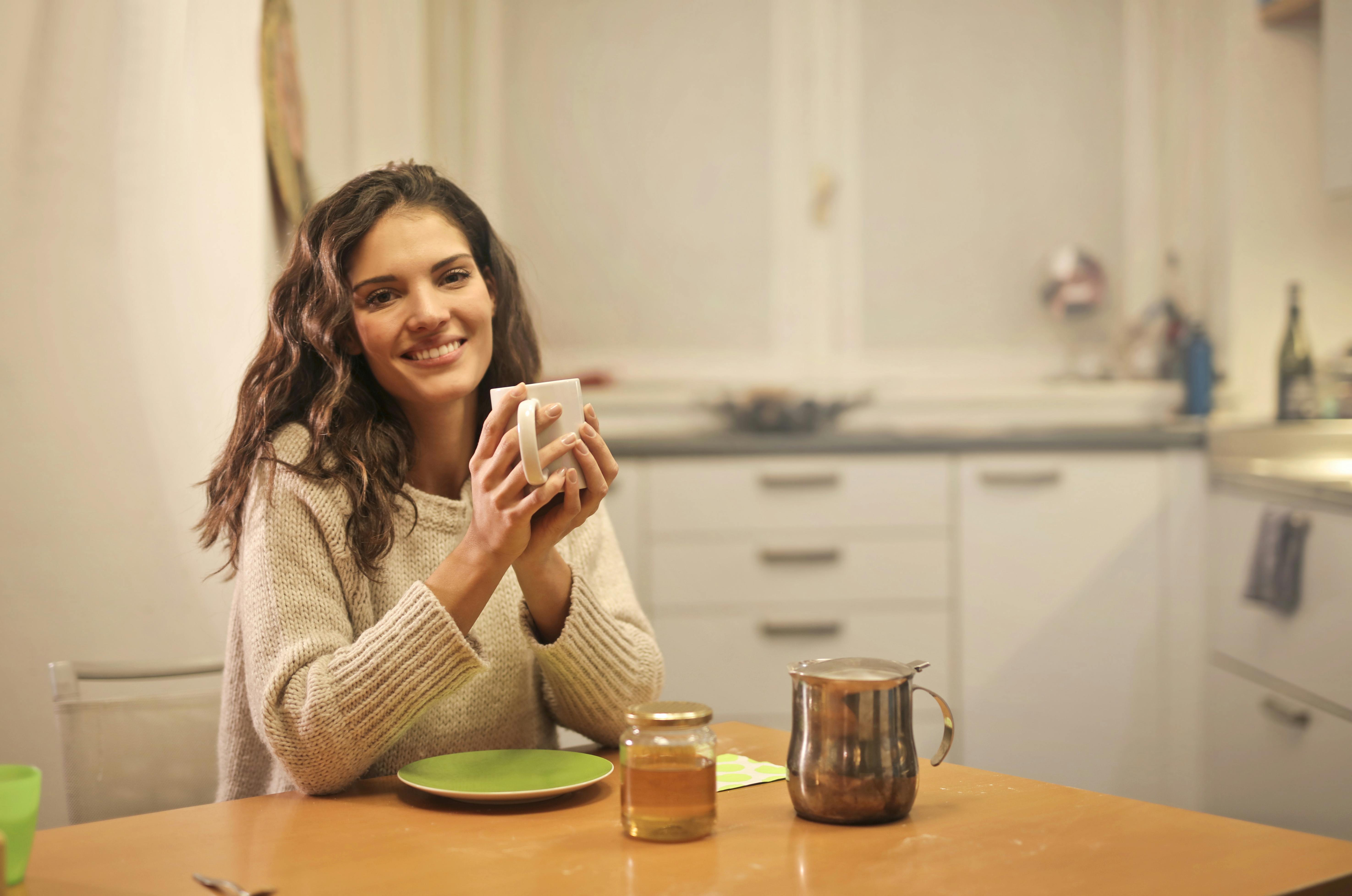 Une femme qui sourit en tenant une tasse | Source : Pexels