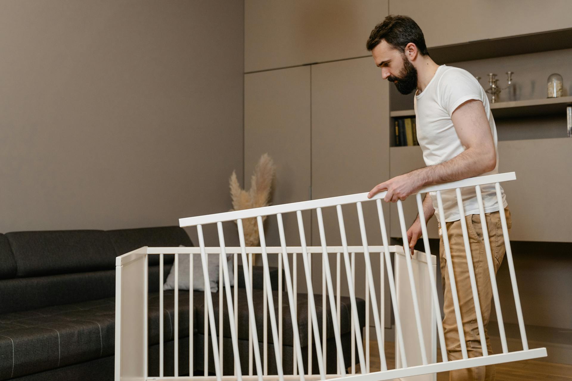 Homme tenant les morceaux d'un berceau de bébé démonté | Source : Pexels
