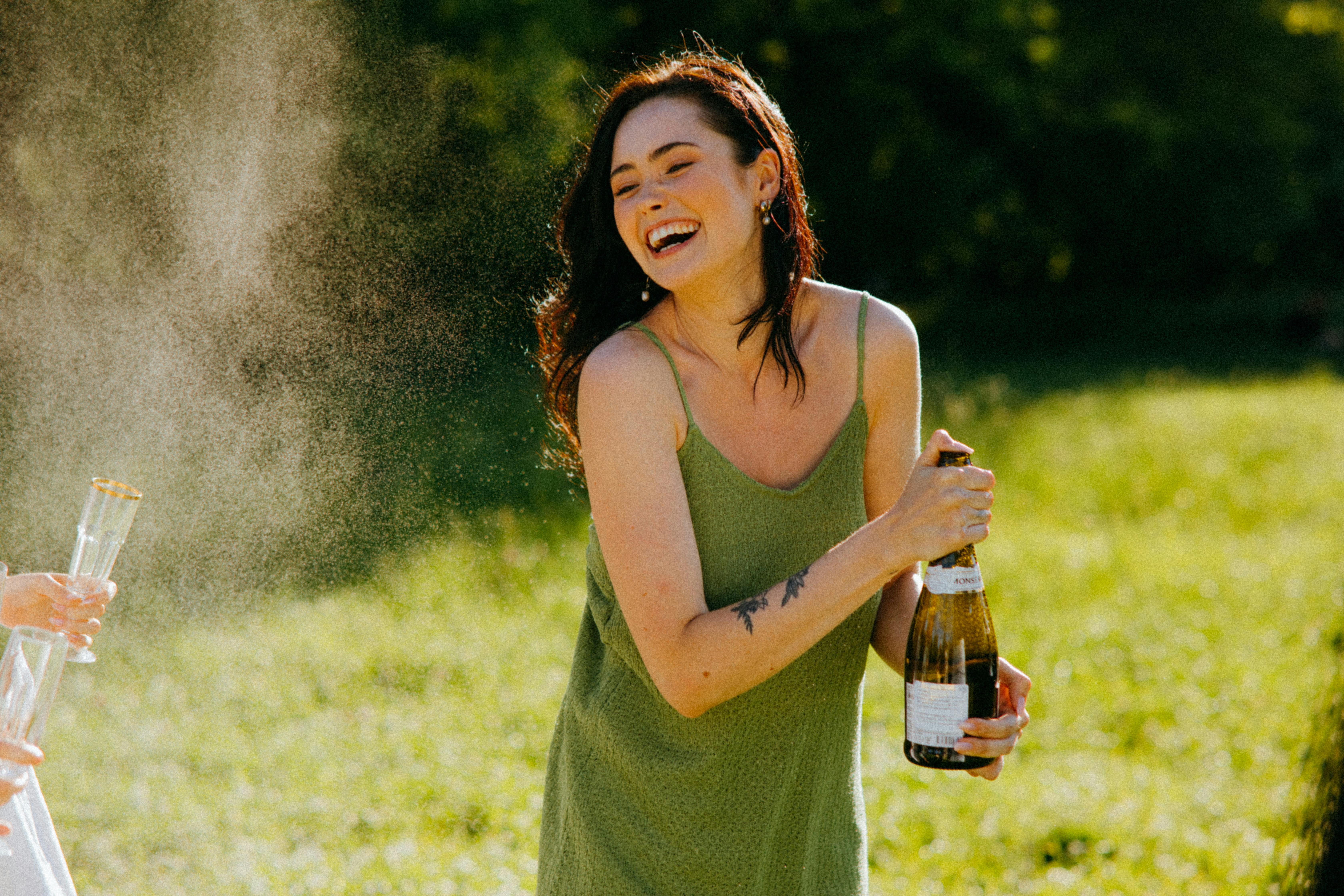 Une femme qui rit en tenant une bouteille | Source : Pexels
