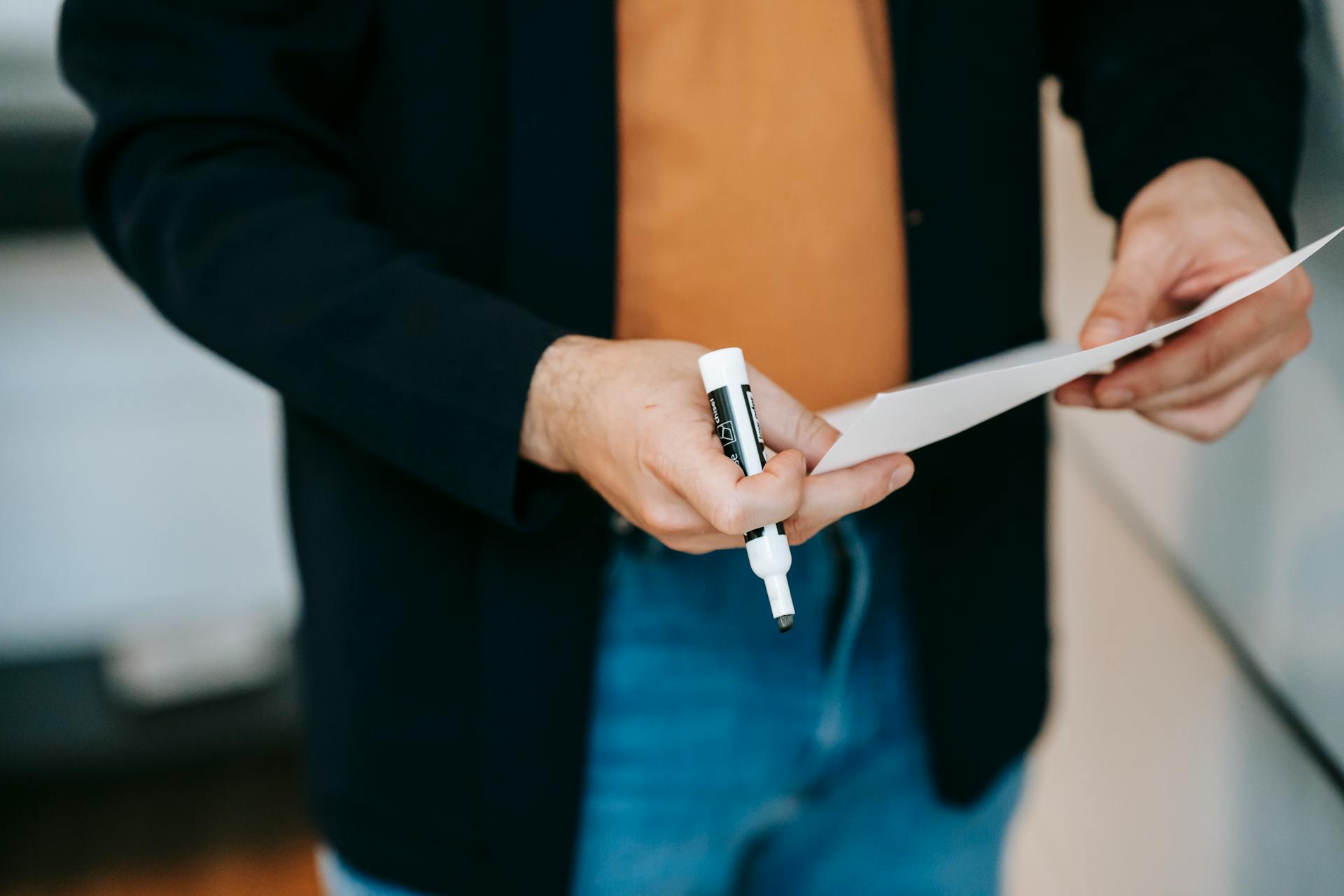 Un homme tenant un marqueur et une feuille de papier | Source : Pexels