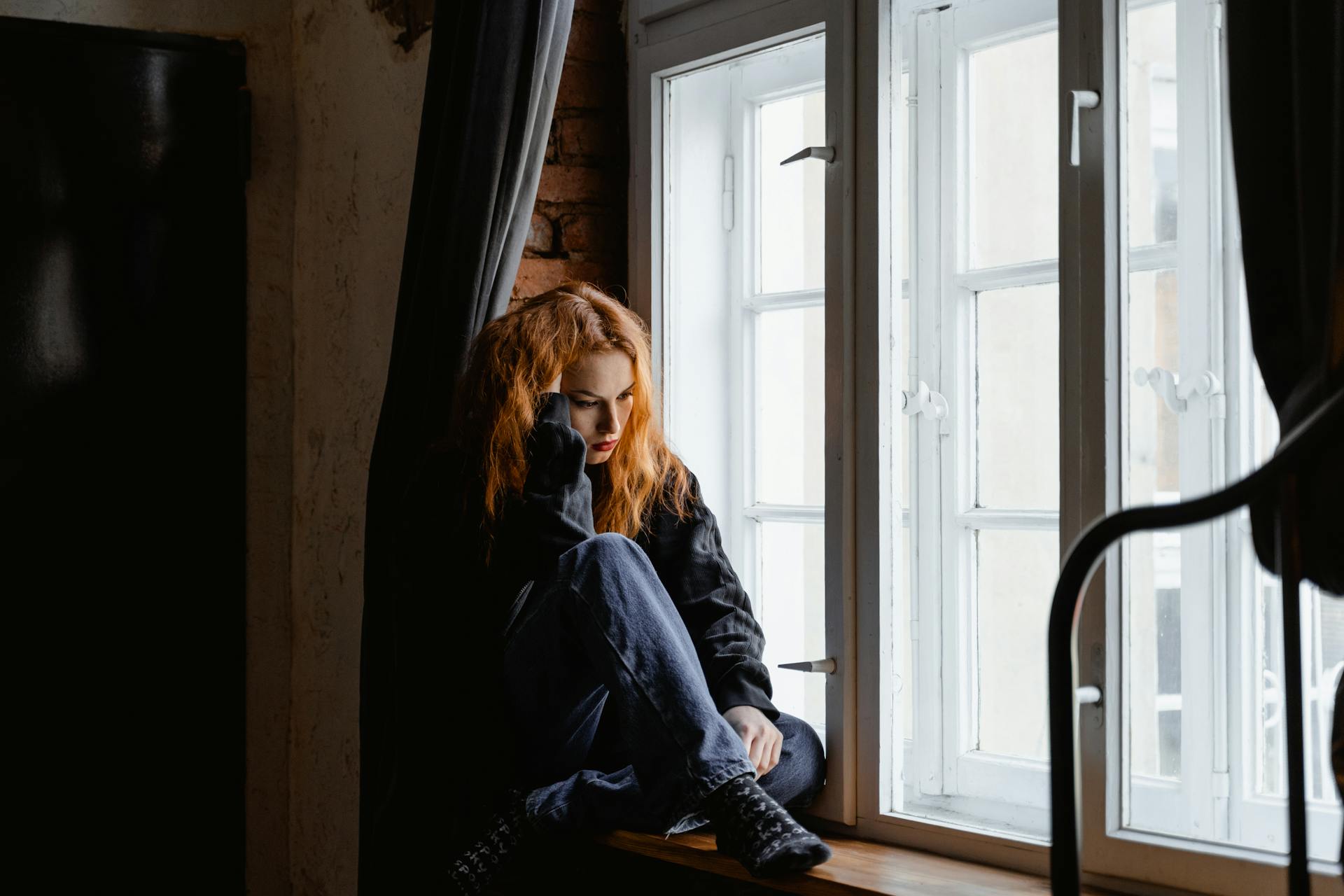 Une femme assise près d'une fenêtre | Source : Pexels