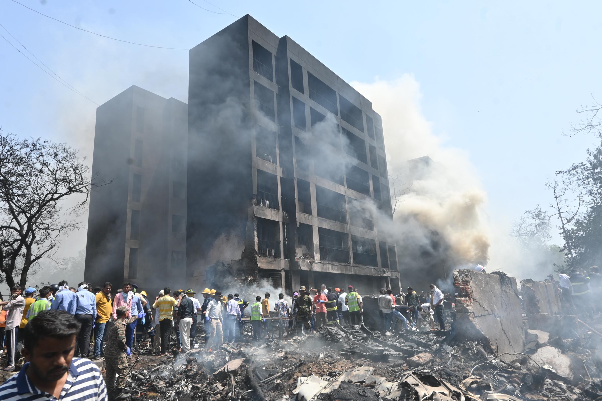 De la fumée s'élève d'un bâtiment endommagé alors que des personnes se rassemblent sur le site de l'accident à Ahmedabad, en Inde, le 12 juin 2025 | Source : Getty Images