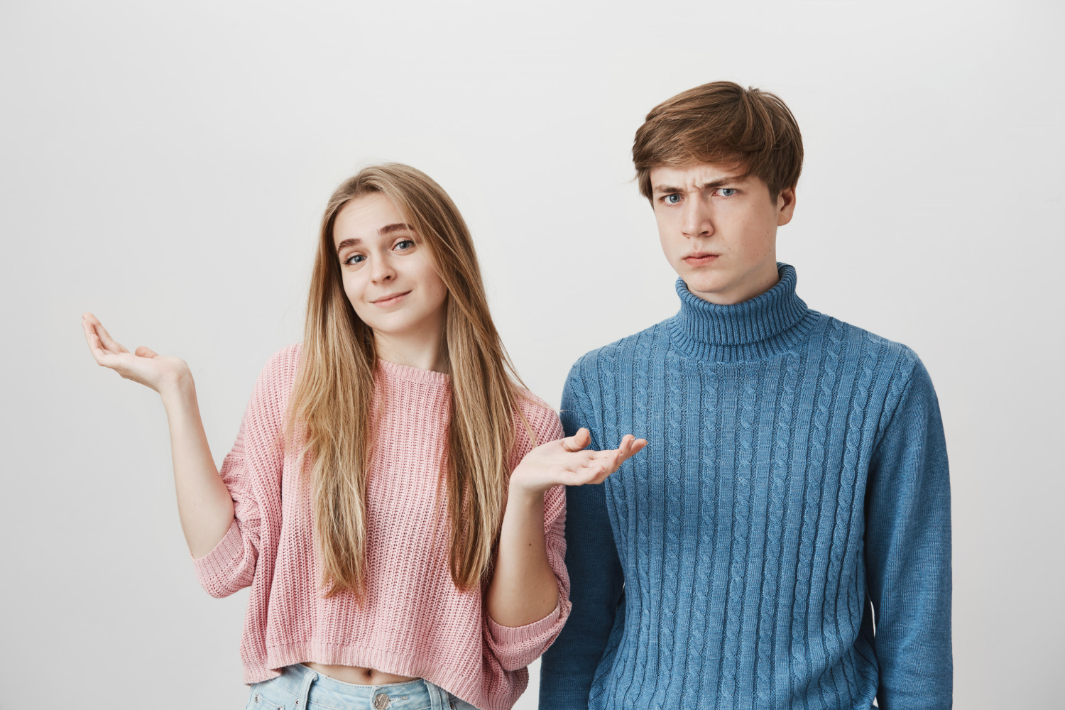 Une jeune fille haussant les épaules à côté d'un adolescent agacé | Source : Freepik
