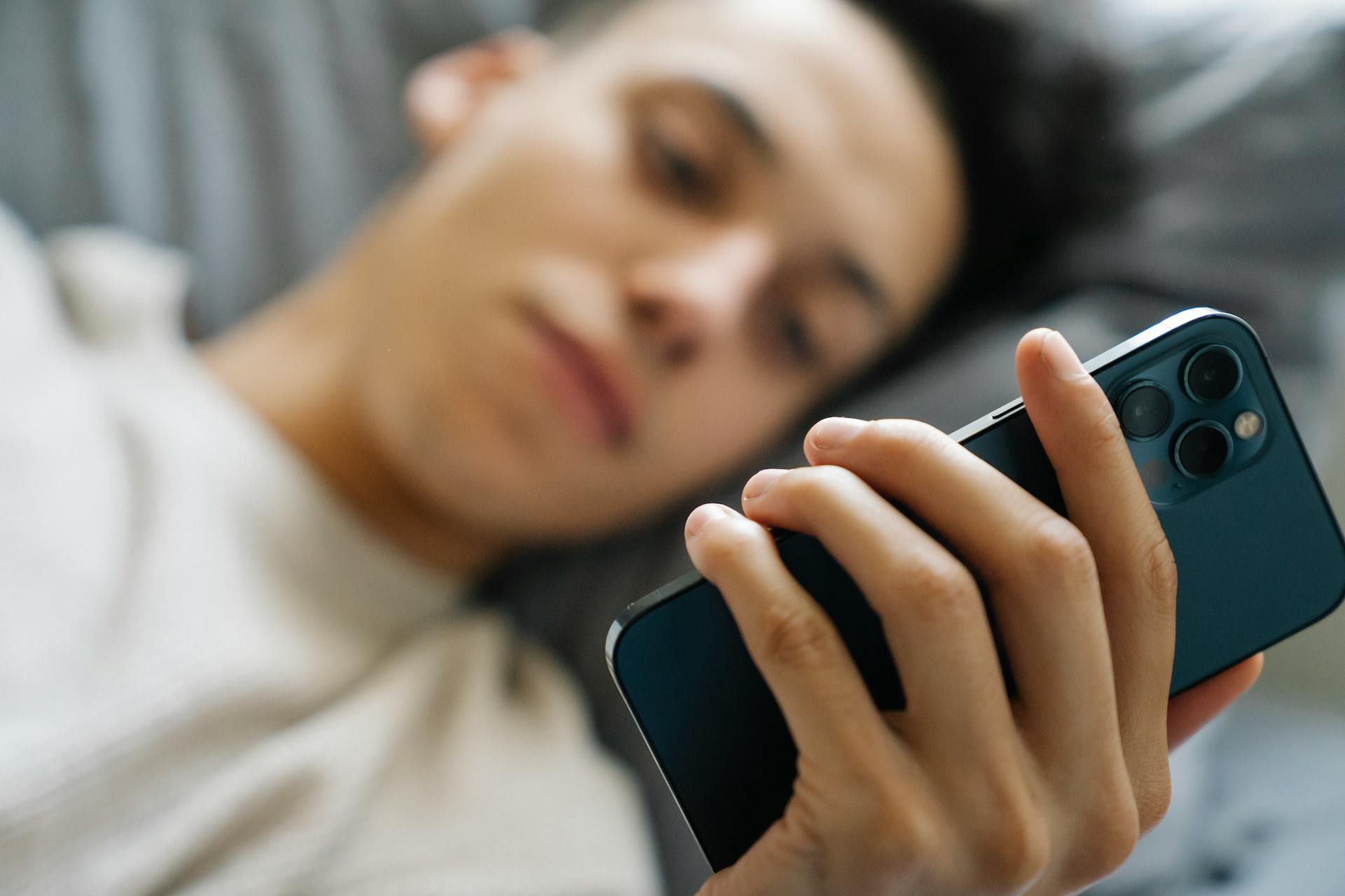 Un jeune homme utilisant son téléphone au lit | Source : Pexels