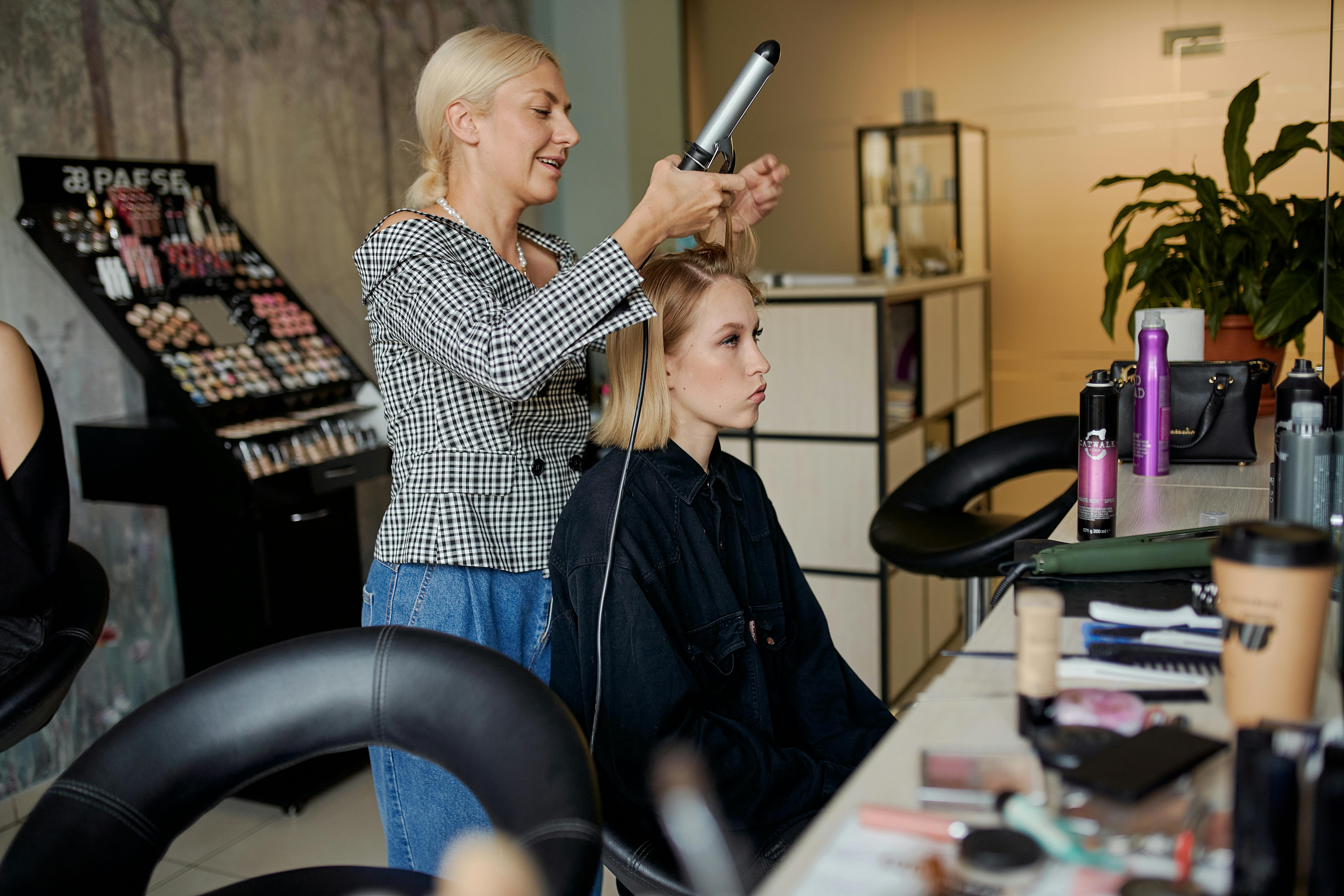 Un coiffeur lissant les cheveux d'une cliente | Source : Pexels