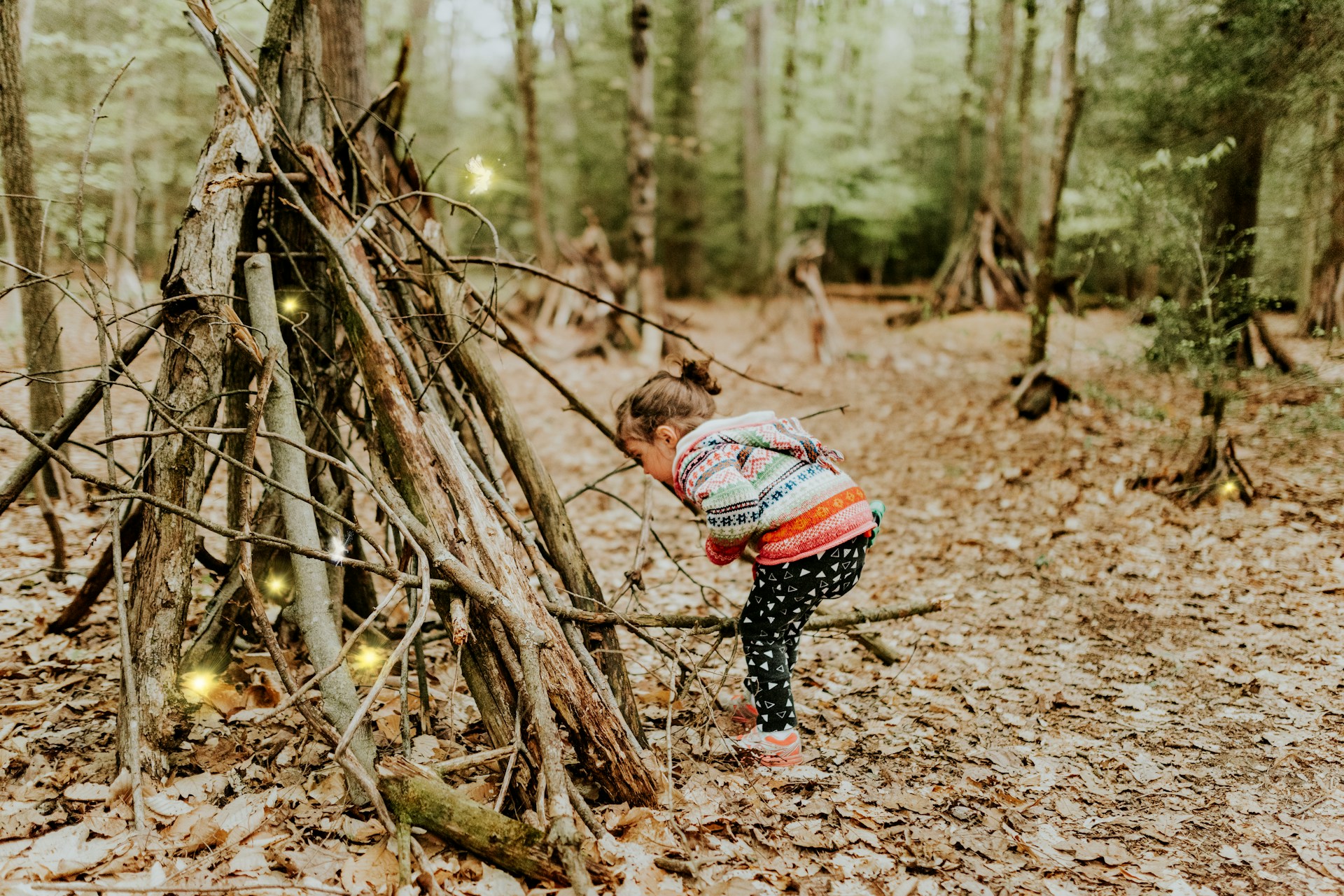 Une petite fille debout près d'un tas de branches | Source : Unsplash