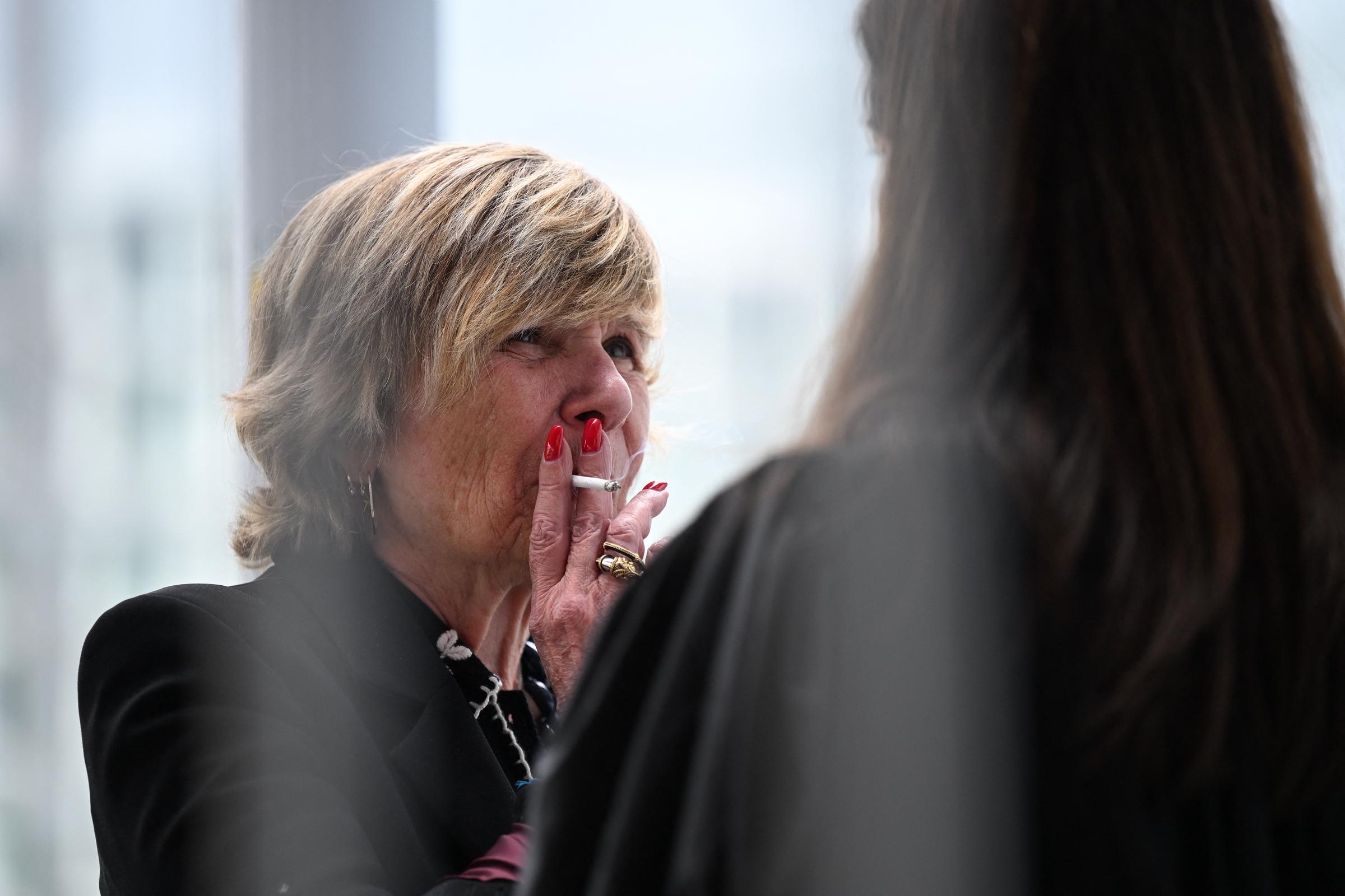 Michèle « Mimi » Marchand, fume une cigarette et s'entretient avec son avocat avant de quitter le tribunal, lors de son procès pour suspicion de chantage à l'encontre de la présentatrice de télévision Karine Le Marchand, au tribunal correctionnel de Paris, le 26 mai 2025 I Source : Getty Images