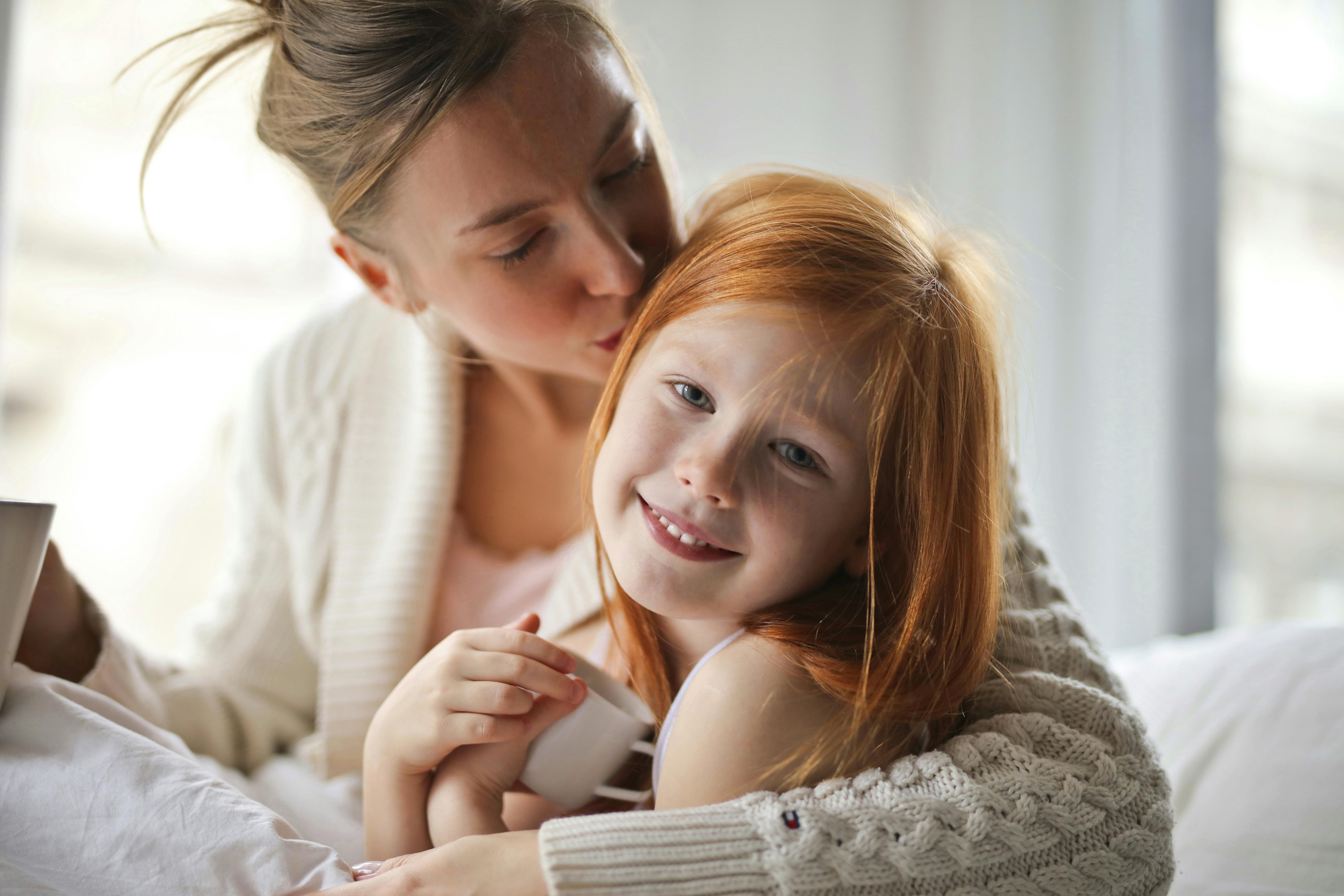 Une mère embrassant la tête de son enfant | Source : Pexels