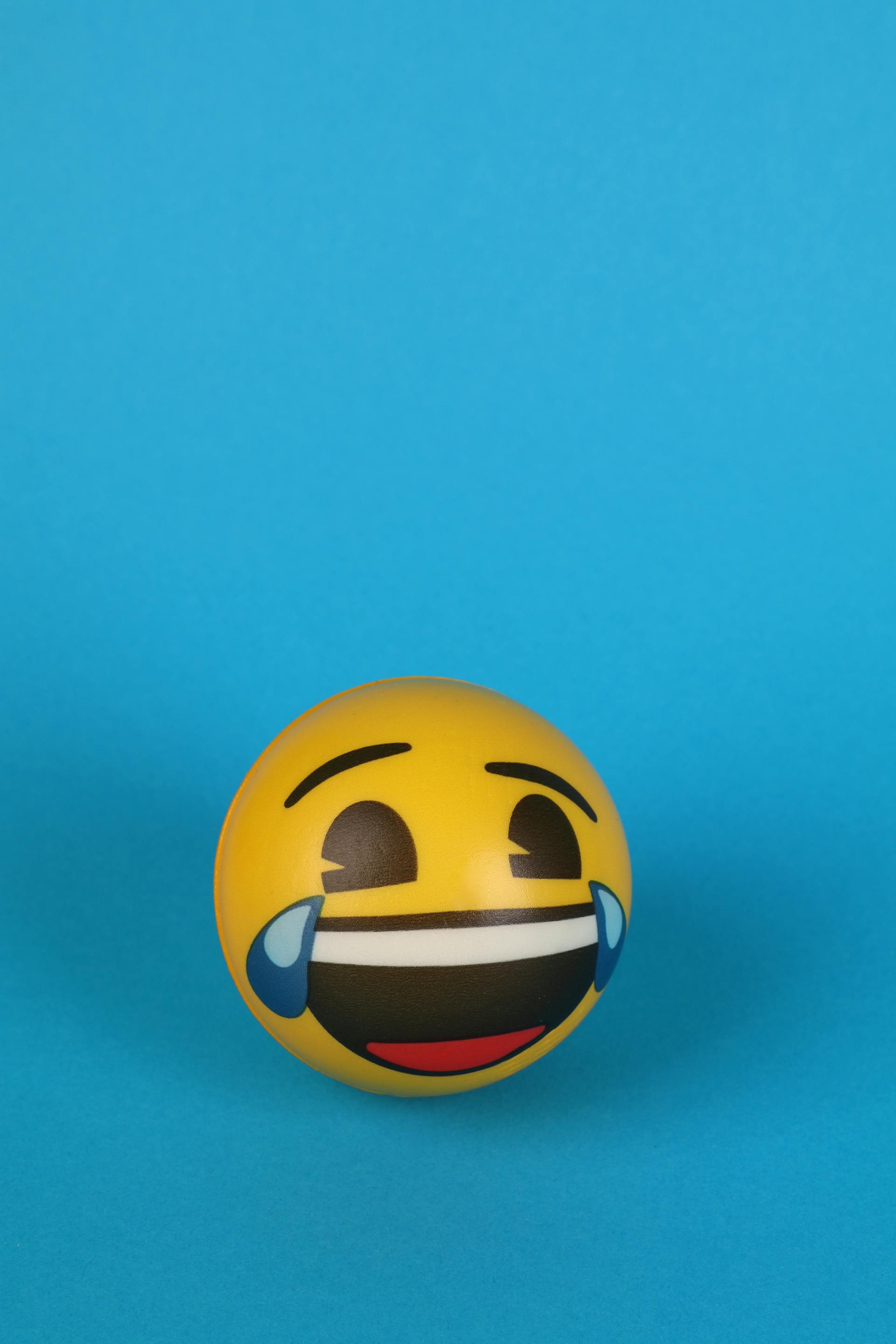 Un emoji rieur aux yeux larmoyants peint sur une balle jaune | Source : Pexels