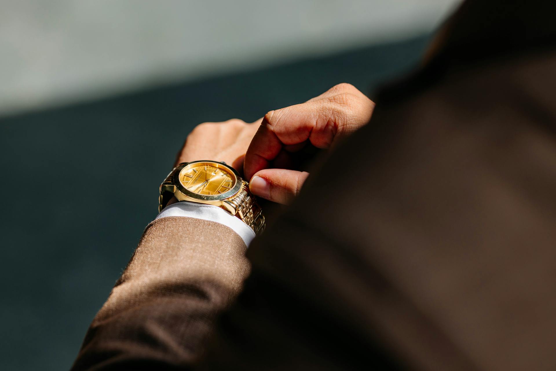 Gros plan sur un homme en costume qui touche sa montre-bracelet | Source : Pexels