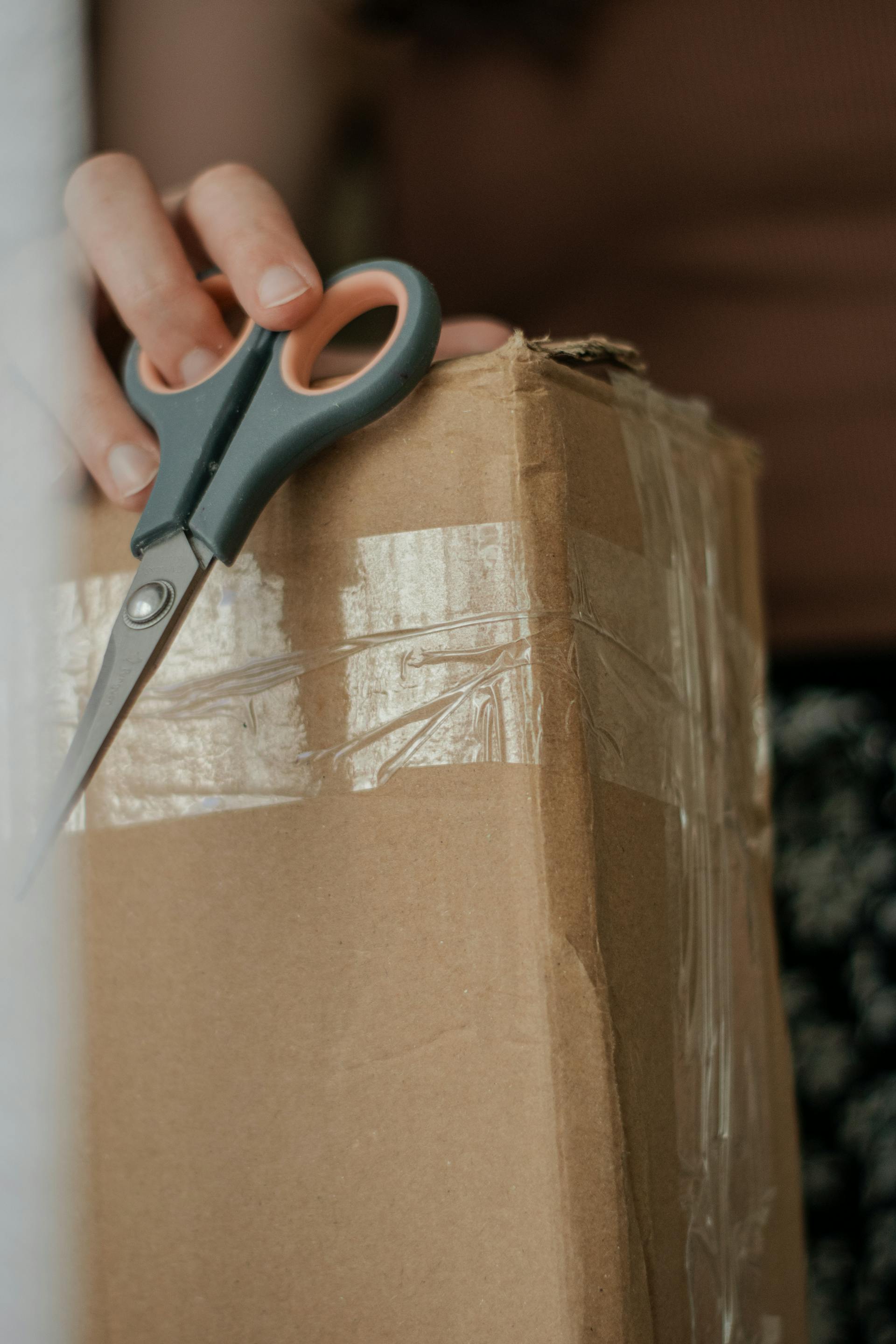 Gros plan d'une femme tenant une boîte en carton et des ciseaux | Source : Pexels