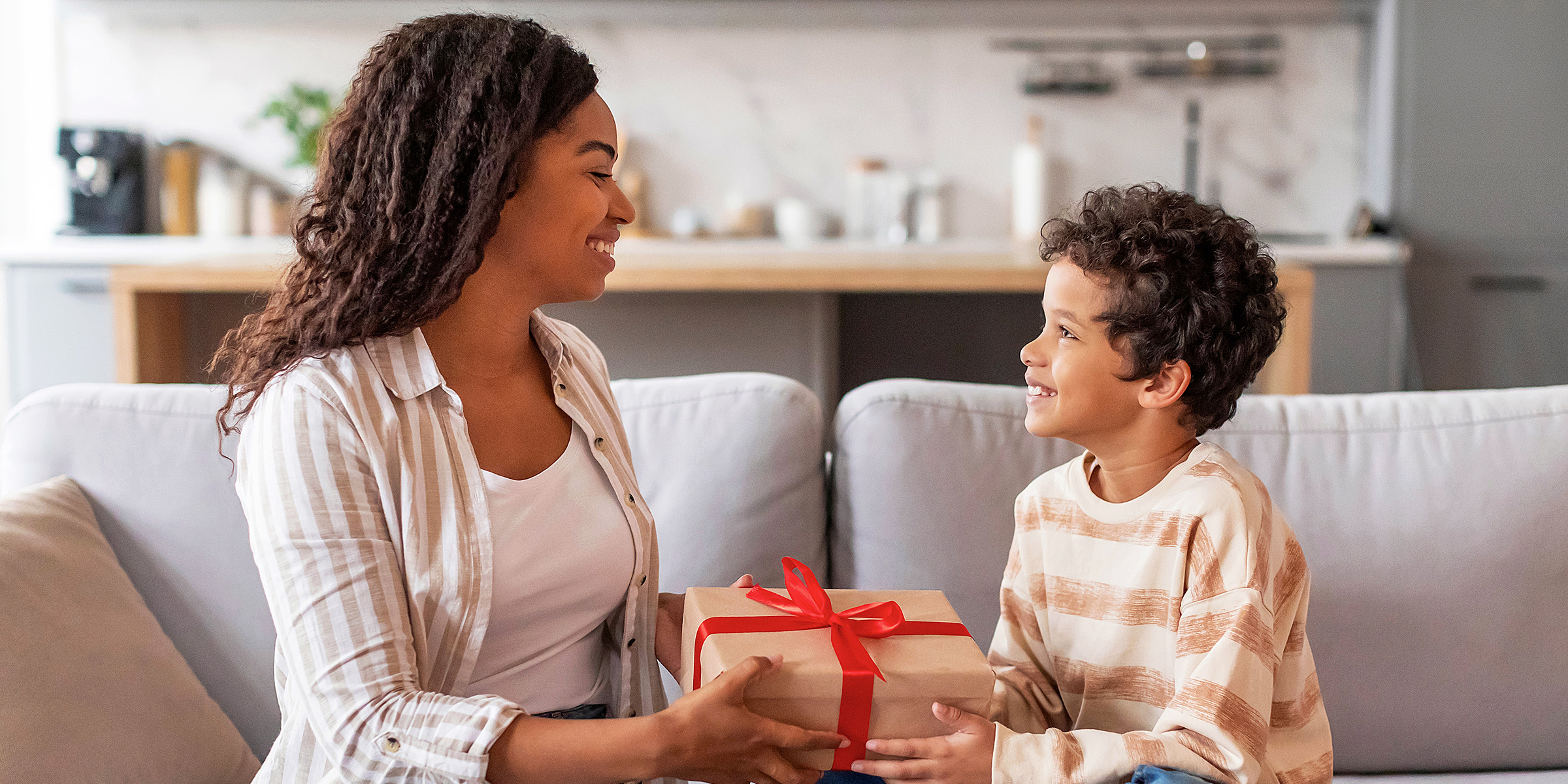 Une femme offrant un cadeau à un jeune garçon | Source : Shutterstock