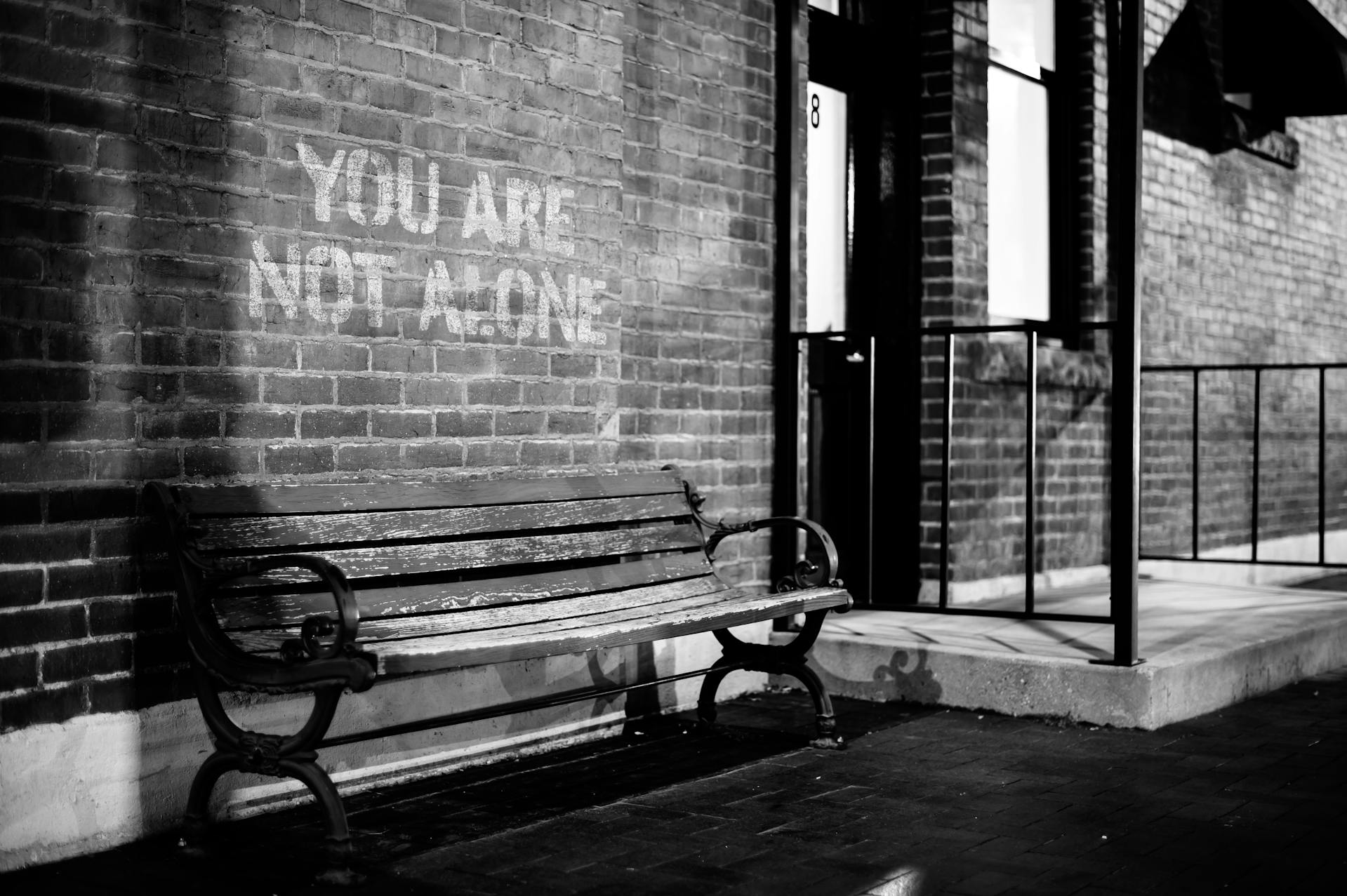 Un banc près d'un mur de briques avec l'inscription « Vous n'êtes pas seul » | Source : Pexels