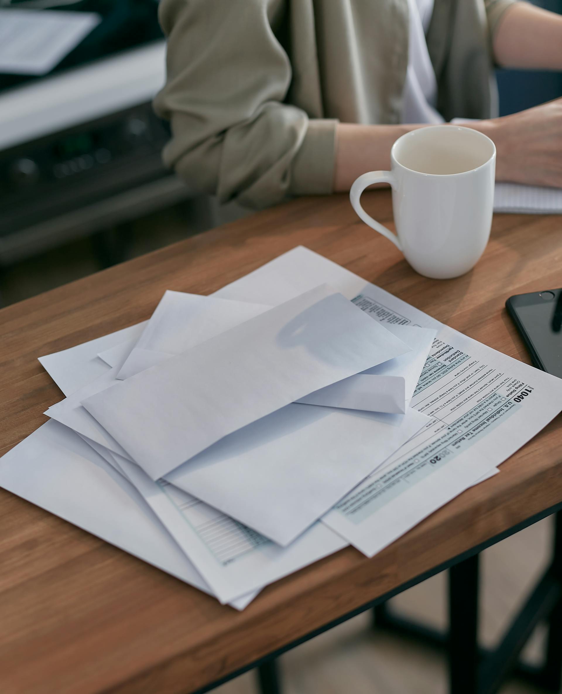 Des enveloppes blanches et documents posés sur une table | Source : Pexels
