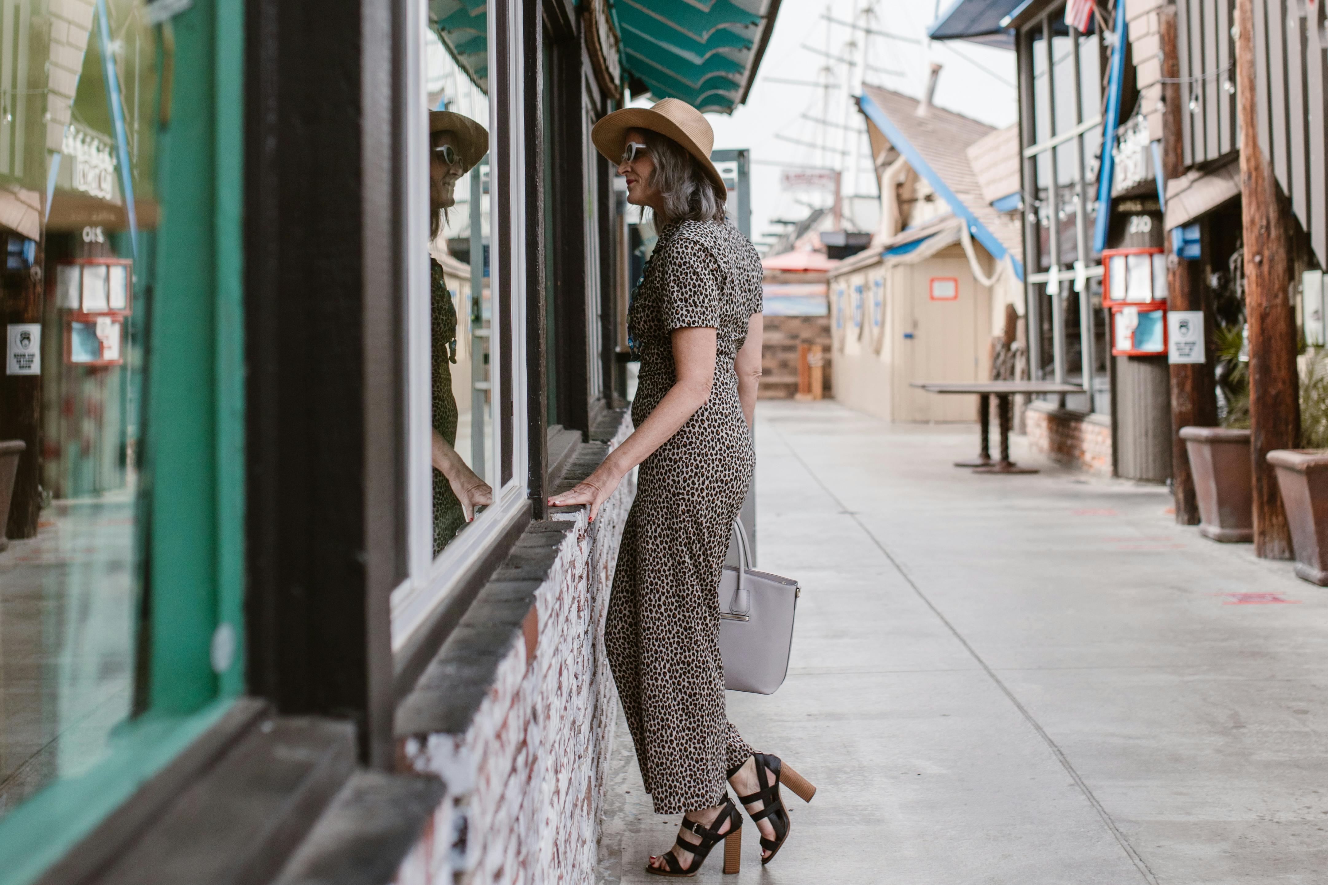 Femme debout à l'extérieur d'un magasin, regardant à travers les fenêtres | Source : Pexels