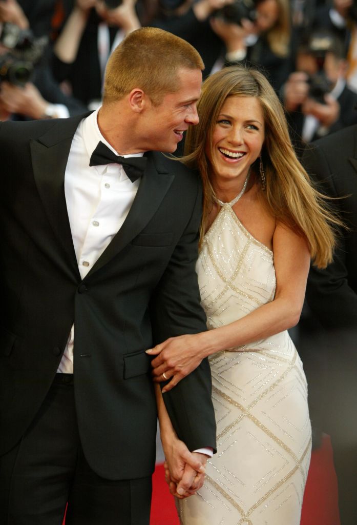 Rayonnante dans une robe blanche à dos nu ornée de détails scintillants sur le tapis rouge, Jennifer Aniston tient la main de Brad Pitt. Elle rayonne de joie et de bonheur, dégageant glamour et élégance.