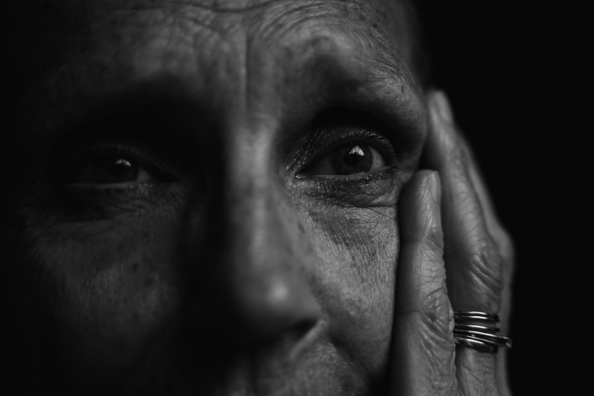 Photo en niveaux de gris d'une personne âgée émotive qui se tient le visage | Source : Pexels
