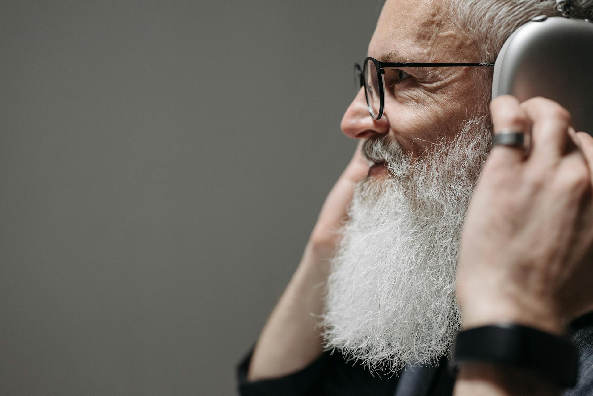 Un homme barbu souriant portant des écouteurs | Source : Pexels