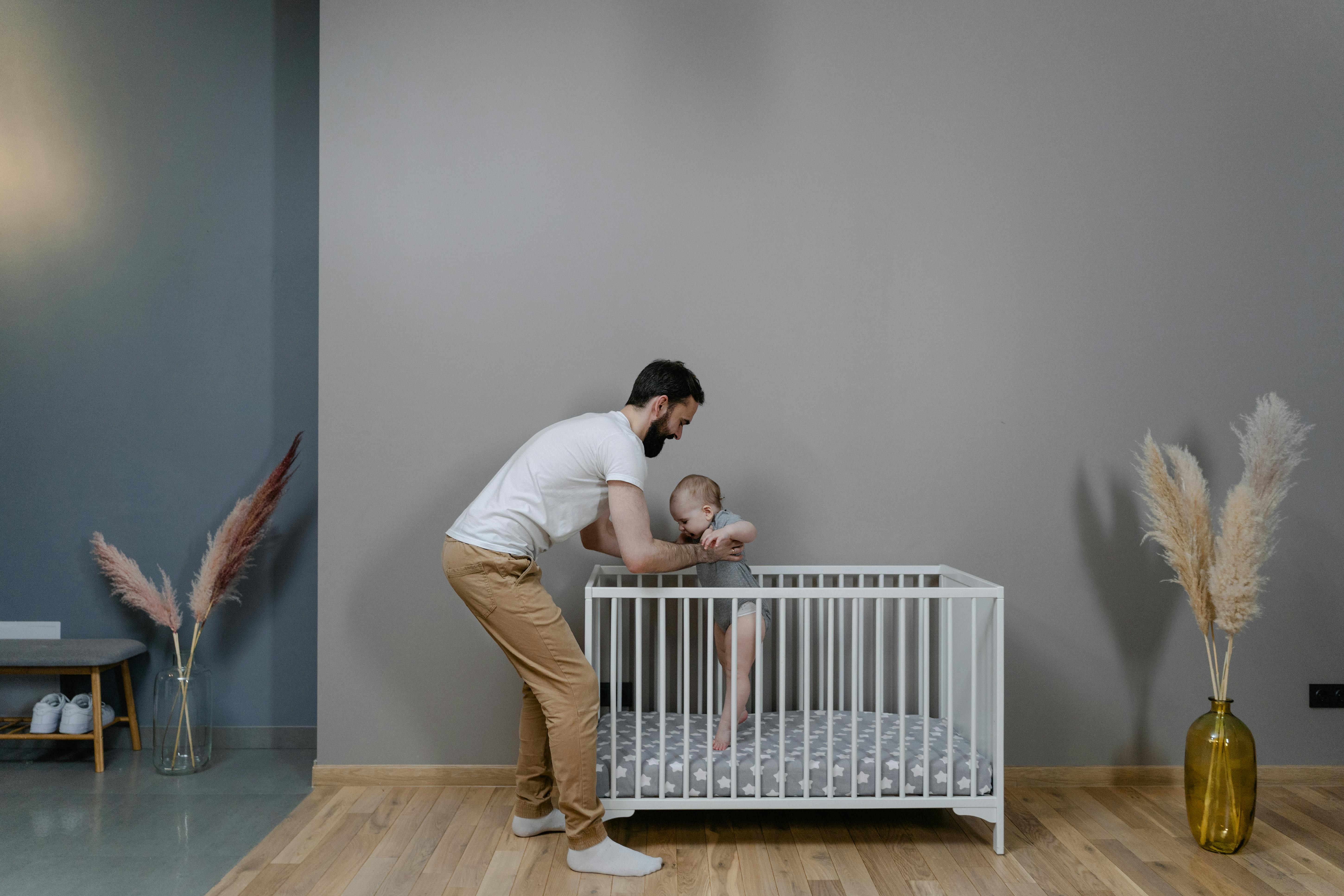 Un homme tenant un bébé dans un berceau | Source : Pexels