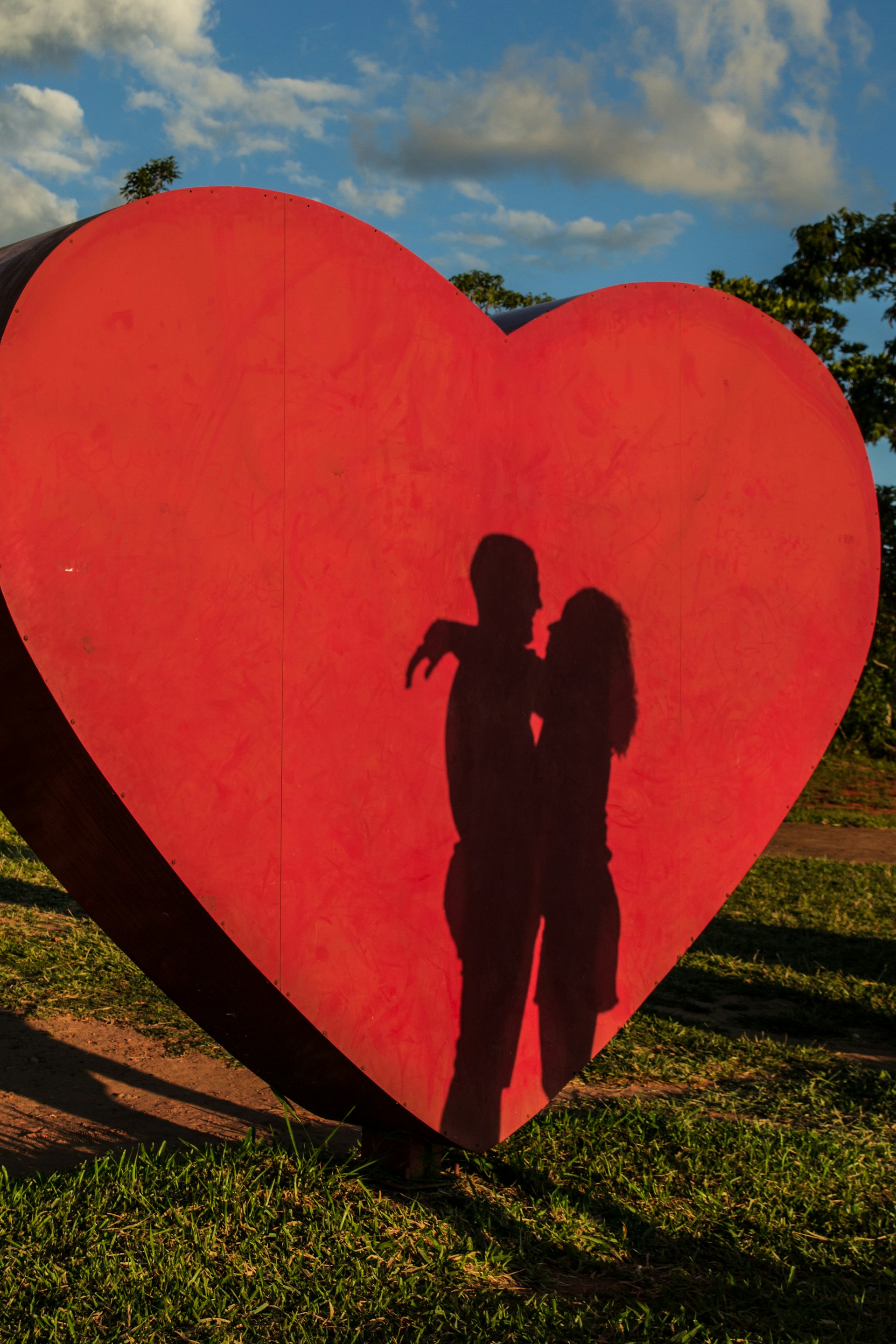 Ombre d'un couple qui s'enlace sur fond de découpe géante en forme de cœur | Source : Unsplash