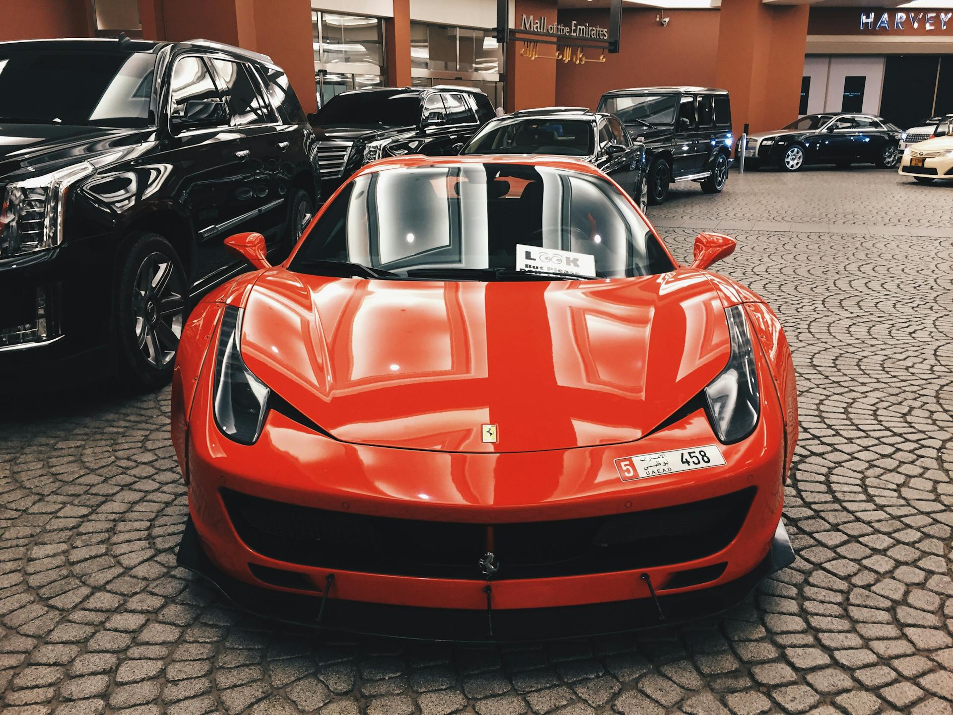Vue de face d'une voiture rouge garée dans un parking avec d'autres voitures en arrière-plan | Source : Pexels