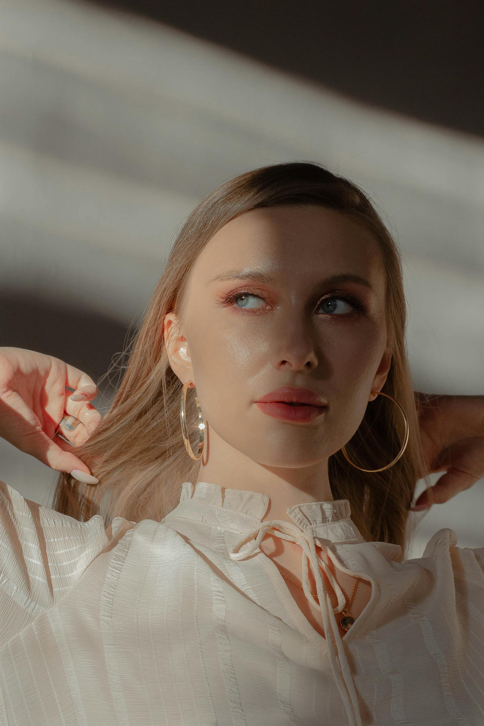Une belle femme avec de grandes boucles d'oreilles et un collier en or fronce les sourcils | Source : Pexels