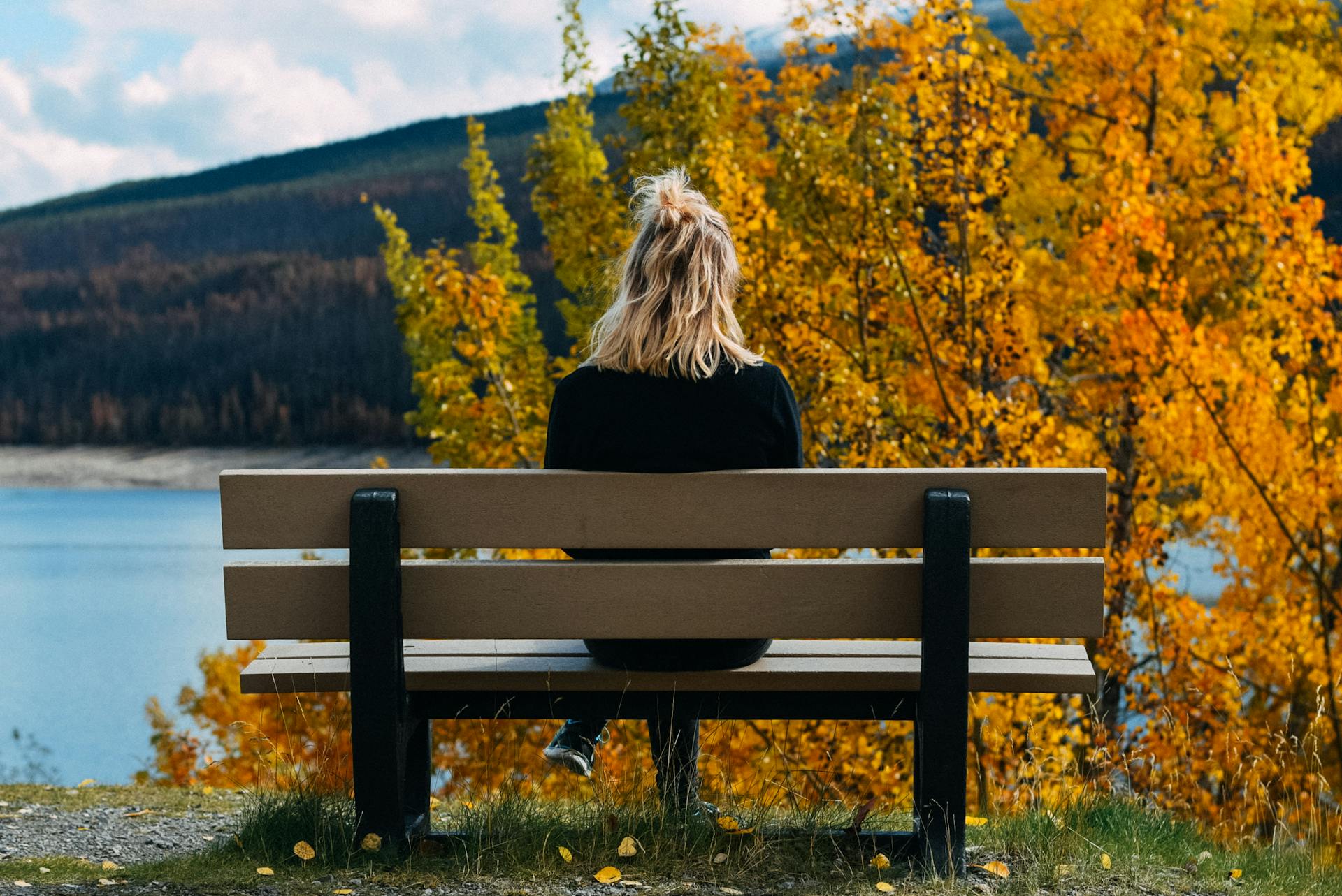 Une femme assise sur un banc et regardant le lac | Source : Pexels
