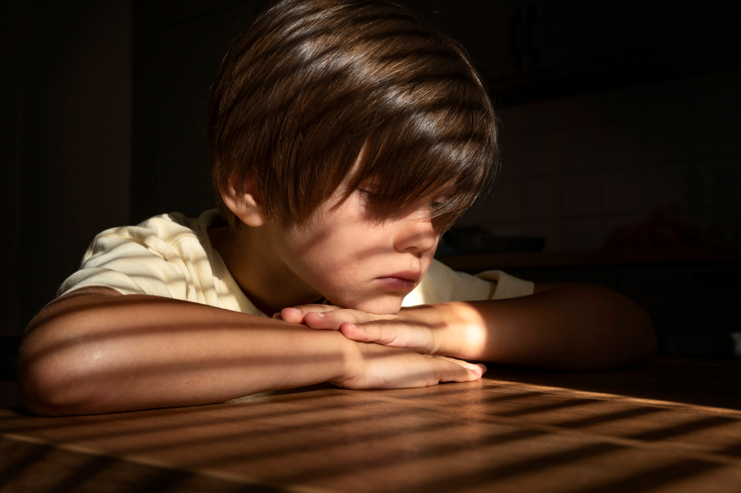 Un garçon triste assis à une table | Source : Freepik