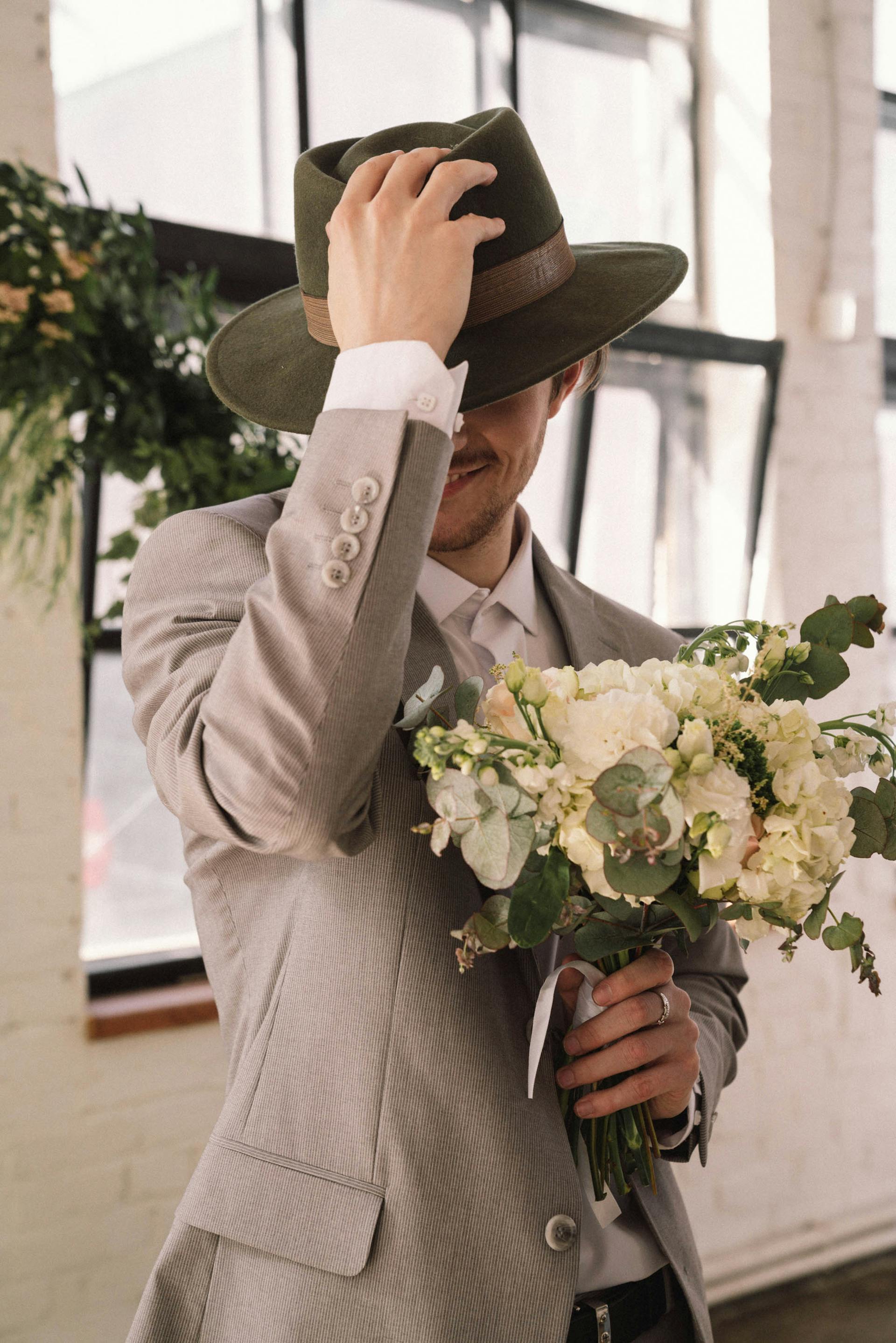Un homme en costume gris et chapeau tenant des fleurs | Source : Pexels