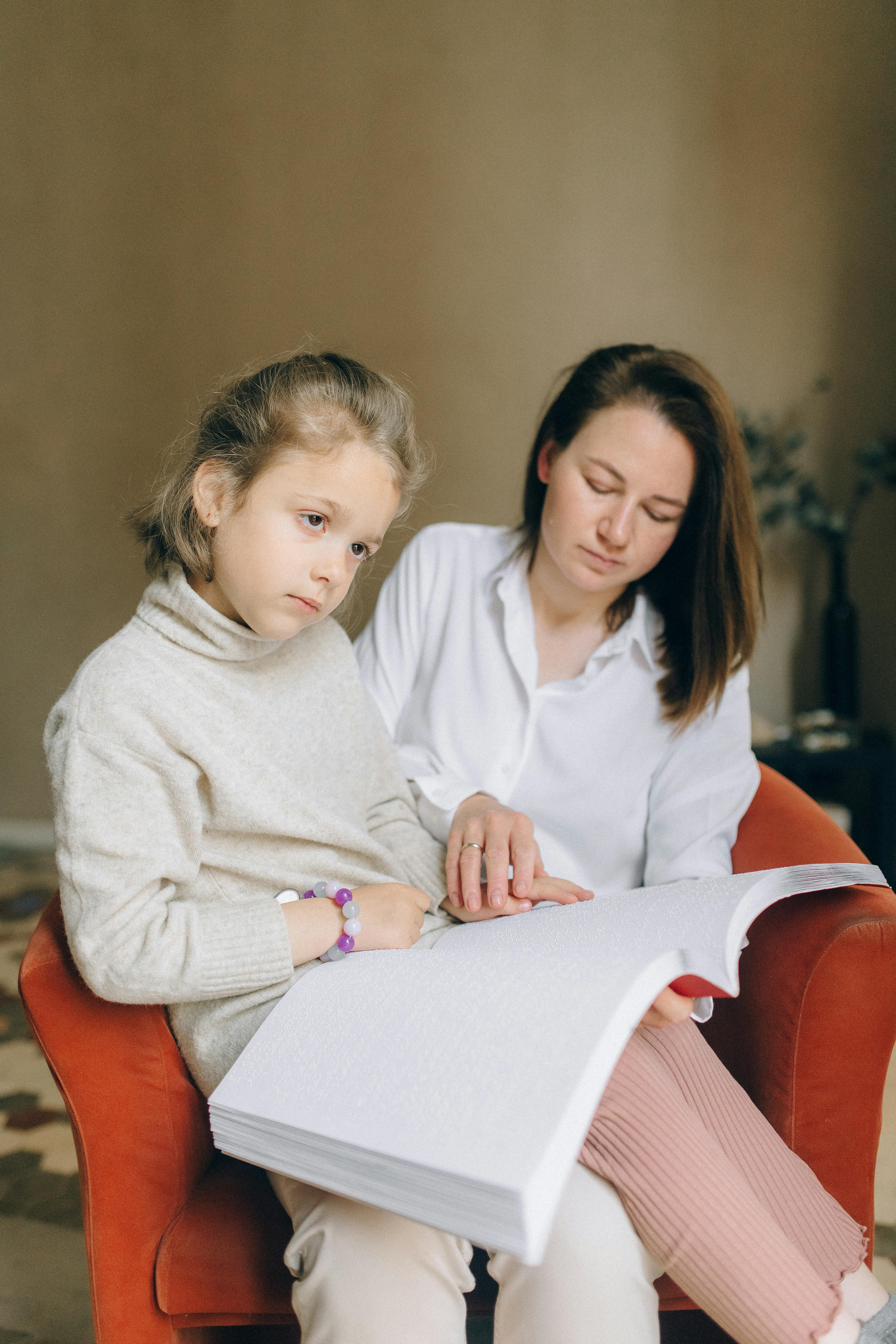 Une femme aidant son enfant à lire | Source : Pexels