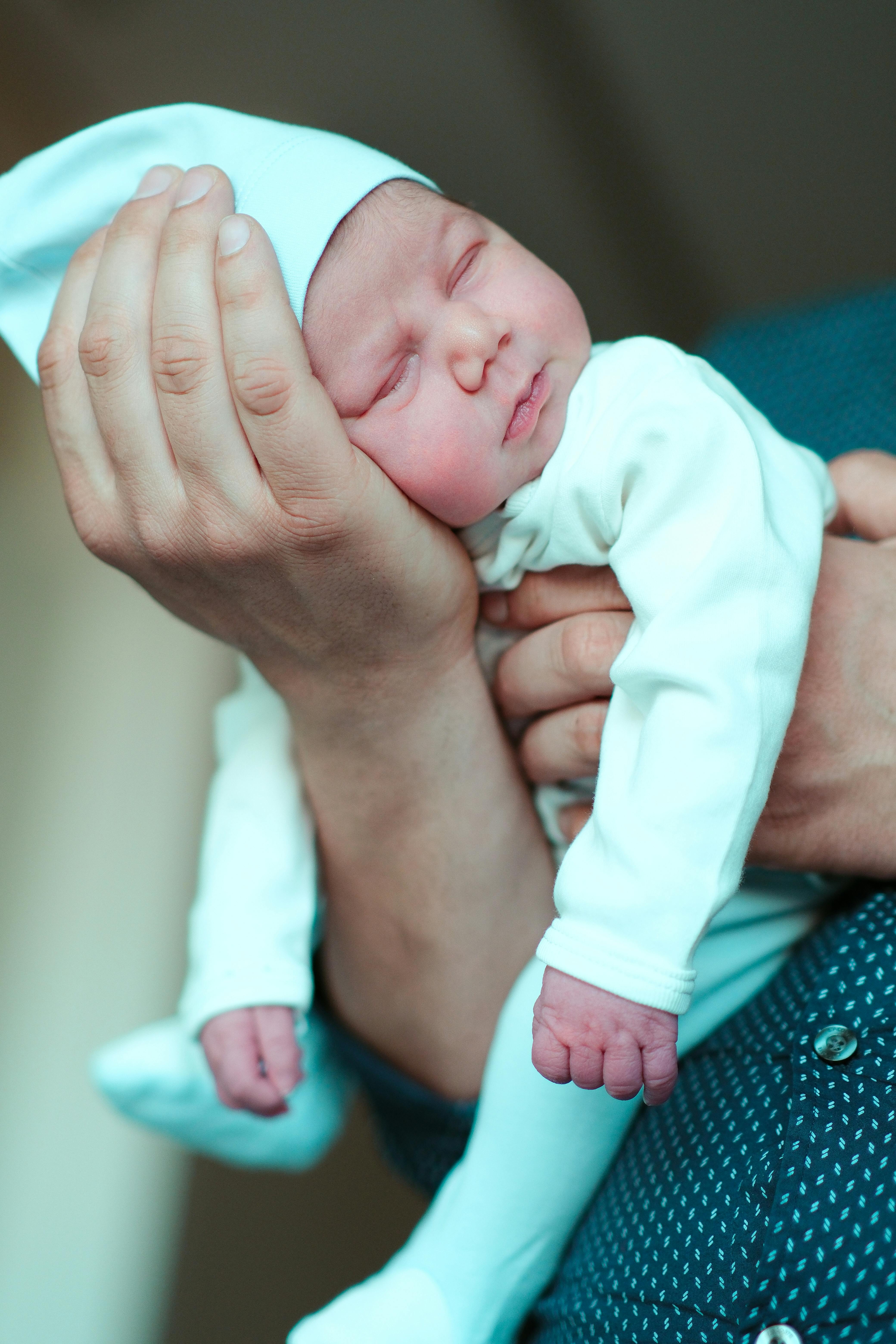 Un bébé endormi dans les bras d'un homme | Source : Pexels