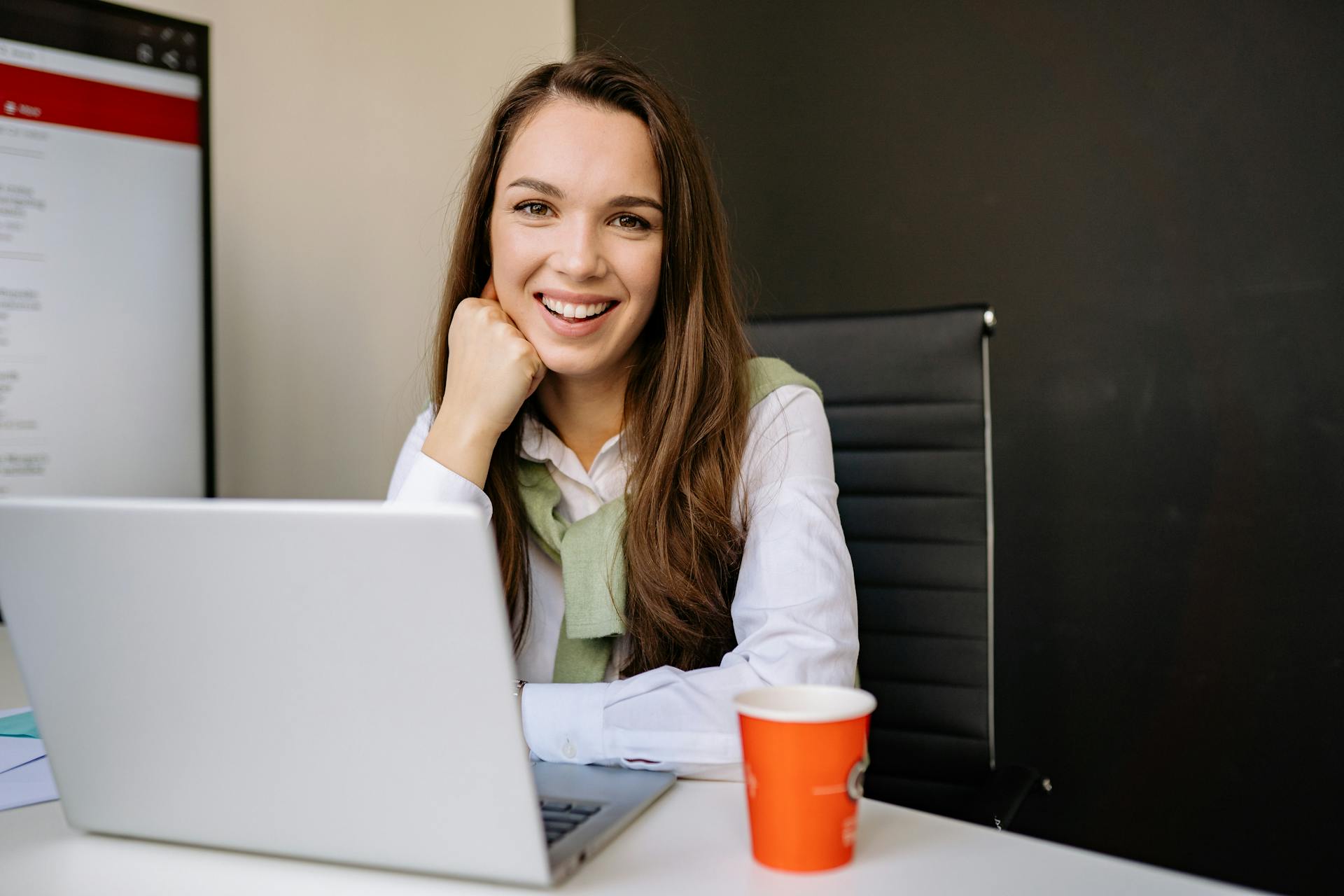 Une femme souriante assise devant un ordinateur portable | Source : Pexels