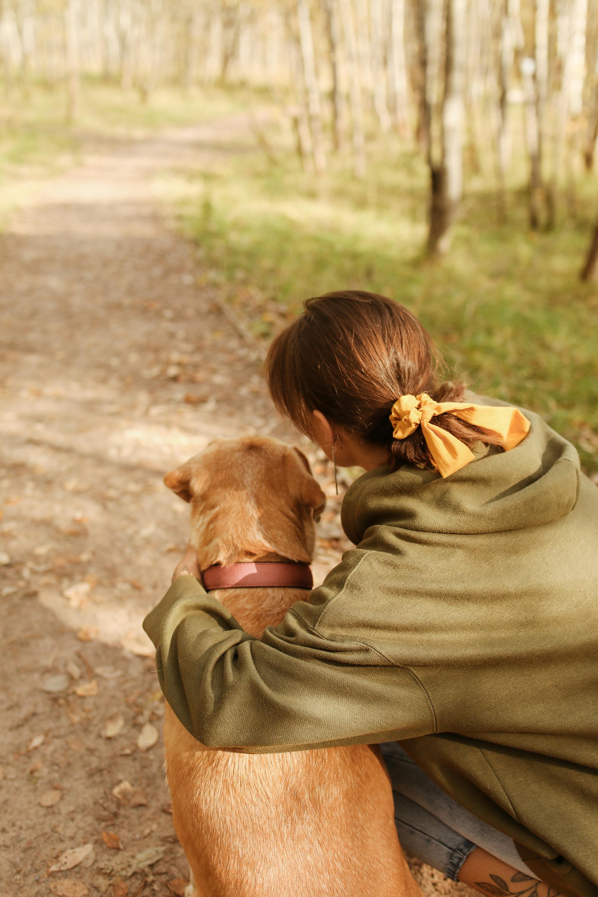 Vue de dos d'une femme agenouillée à côté de son chien | Source : Pexels