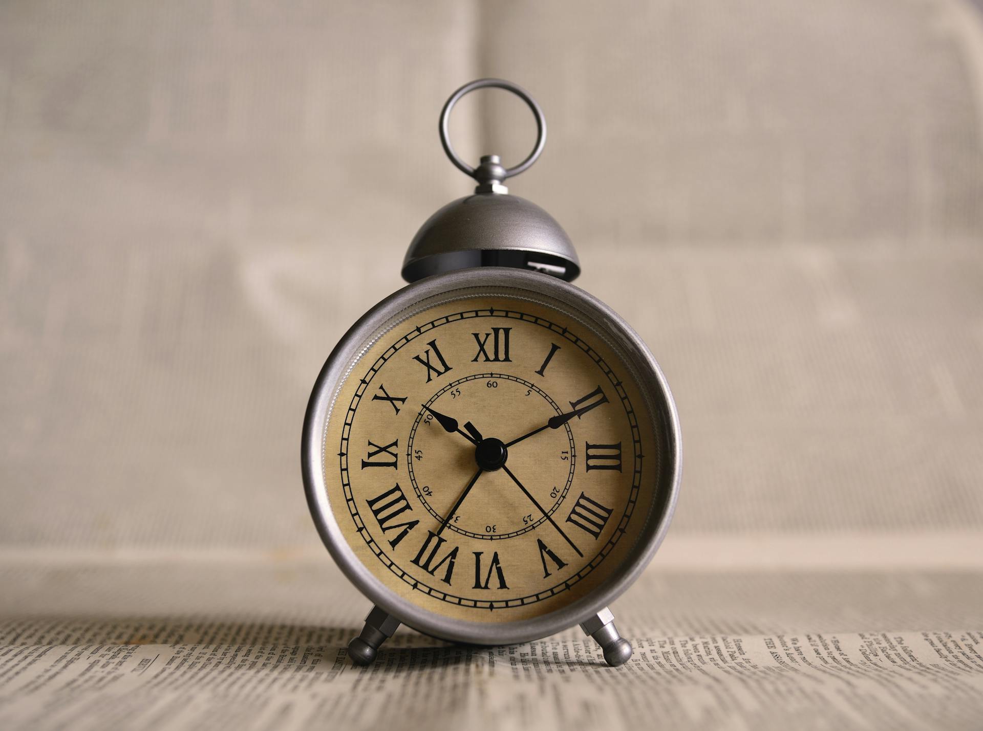 Une vieille horloge sur un morceau de journal | Source : Pexels