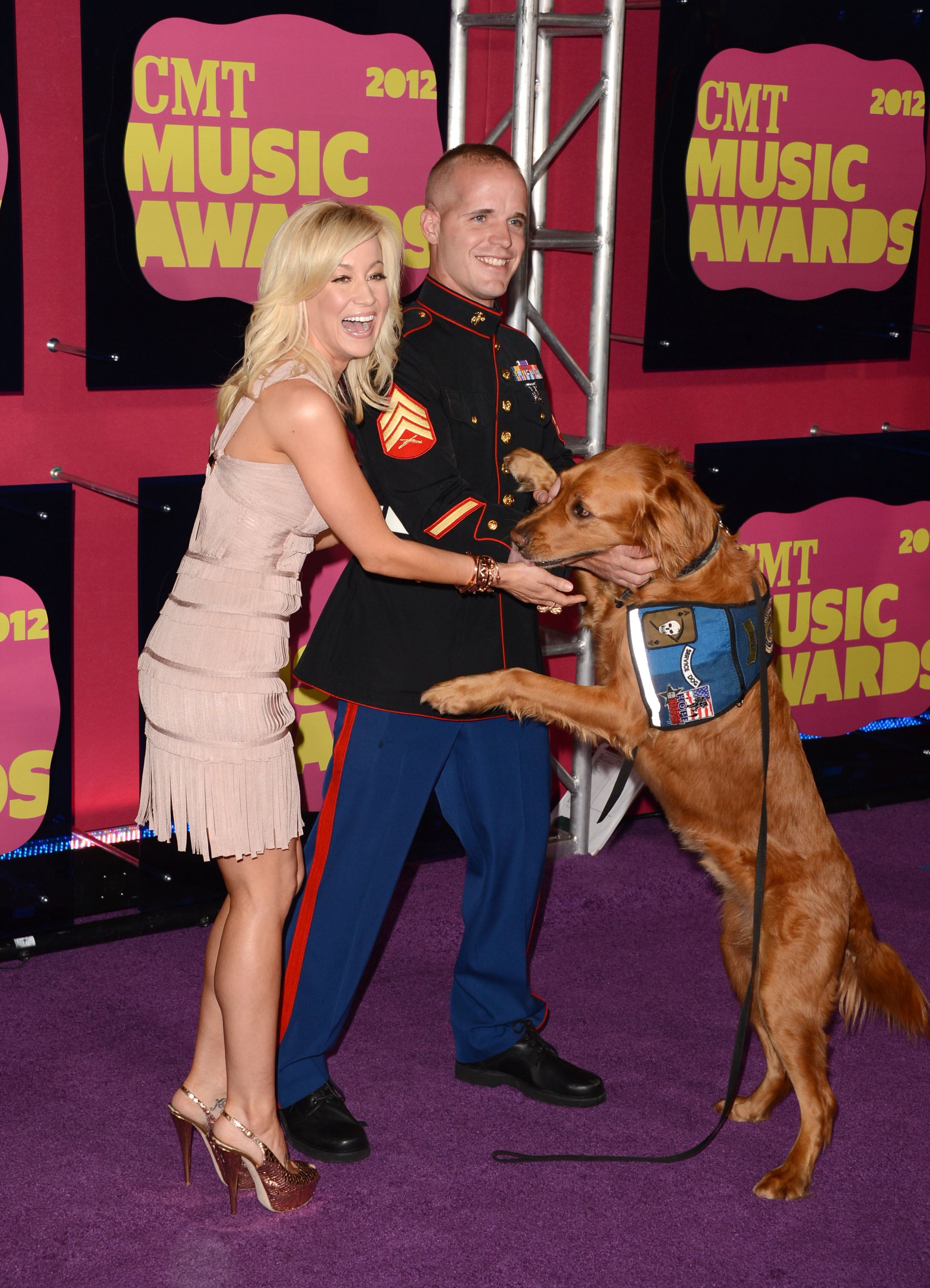 Kellie Pickler salue un chien d'assistance aux côtés de Nigel Max Edge à son arrivée aux Country Music Television (CMT) Awards le 6 juin 2012 | Source : Getty Images